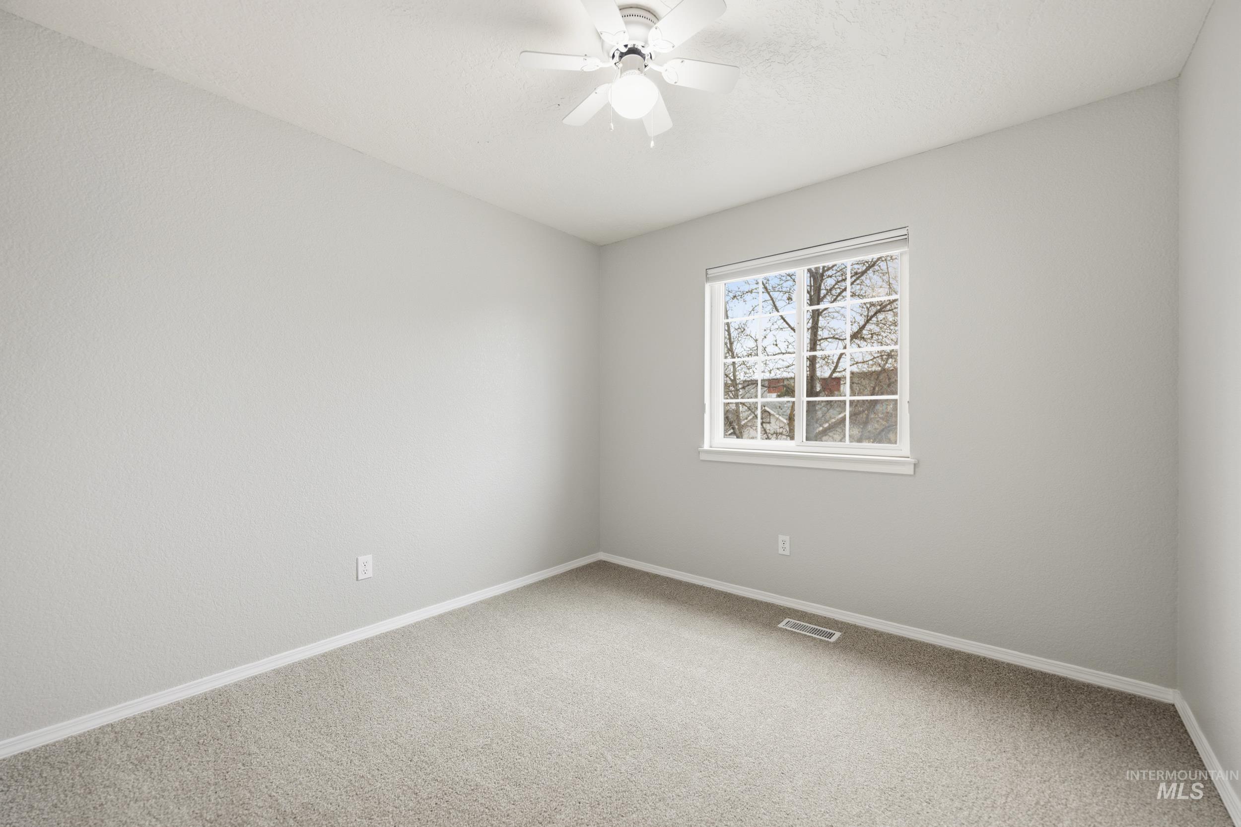 Carpeted spare room featuring baseboards and a ceiling fan
