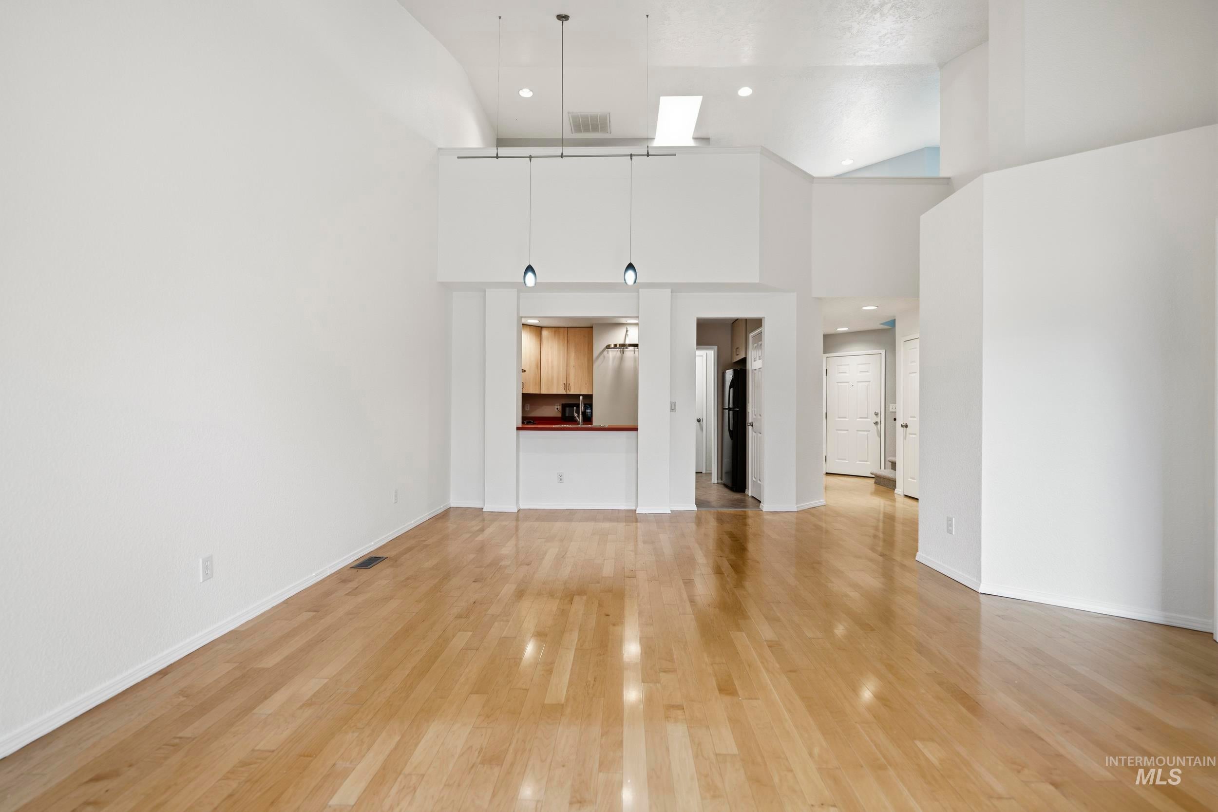 Unfurnished living room featuring recessed lighting, light wood-type flooring, and a high ceiling