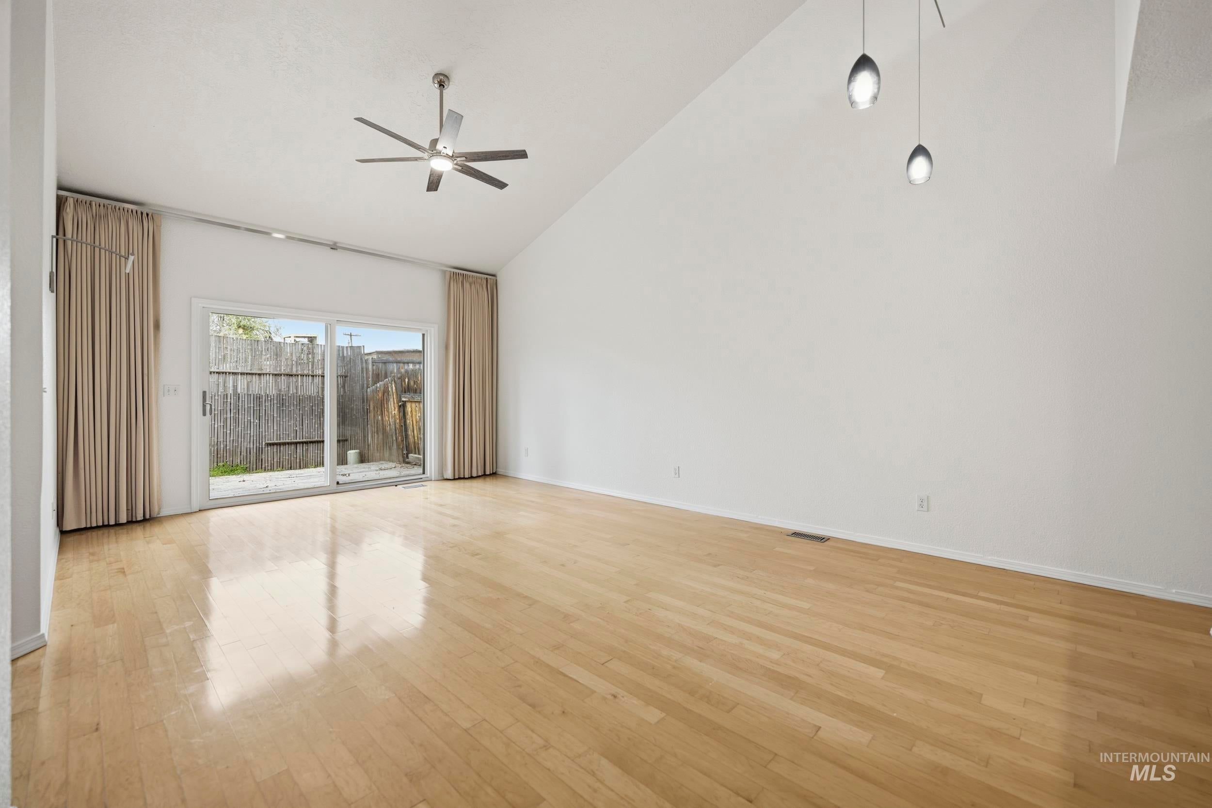 Unfurnished room featuring vaulted ceiling, light wood finished floors, and a ceiling fan