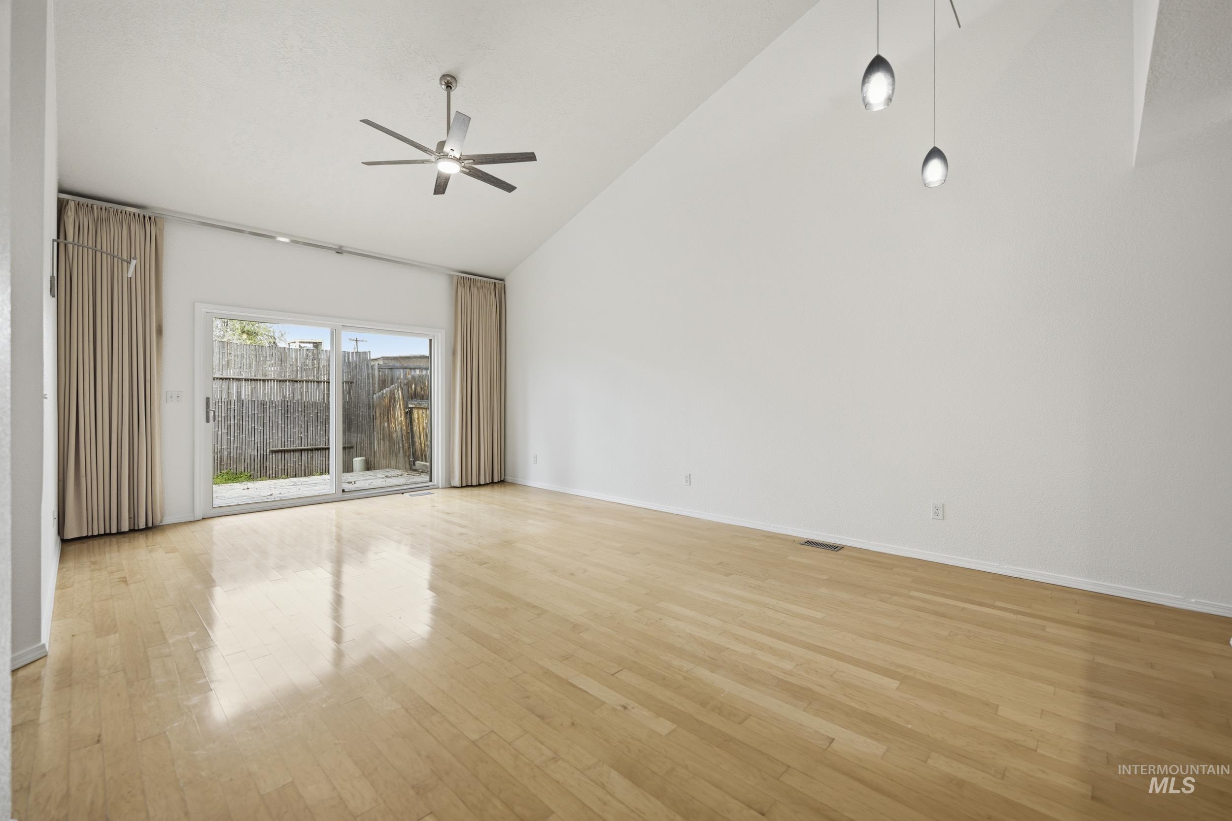 Unfurnished room featuring vaulted ceiling, light wood finished floors, and a ceiling fan