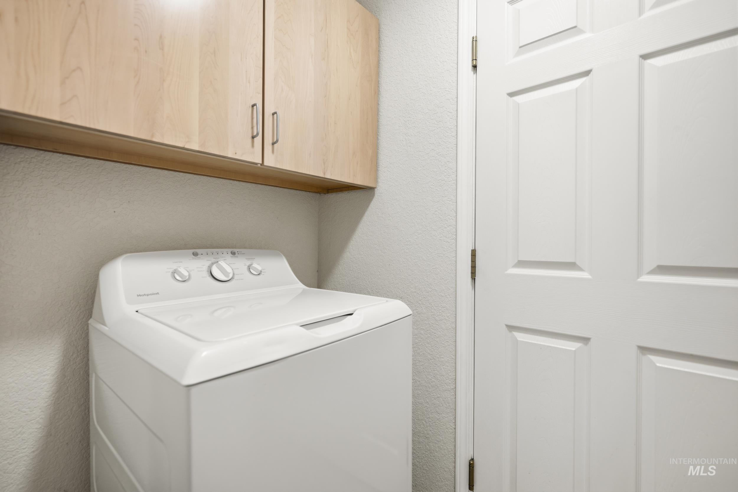 Laundry area featuring washer / clothes dryer, a textured wall, and cabinet space