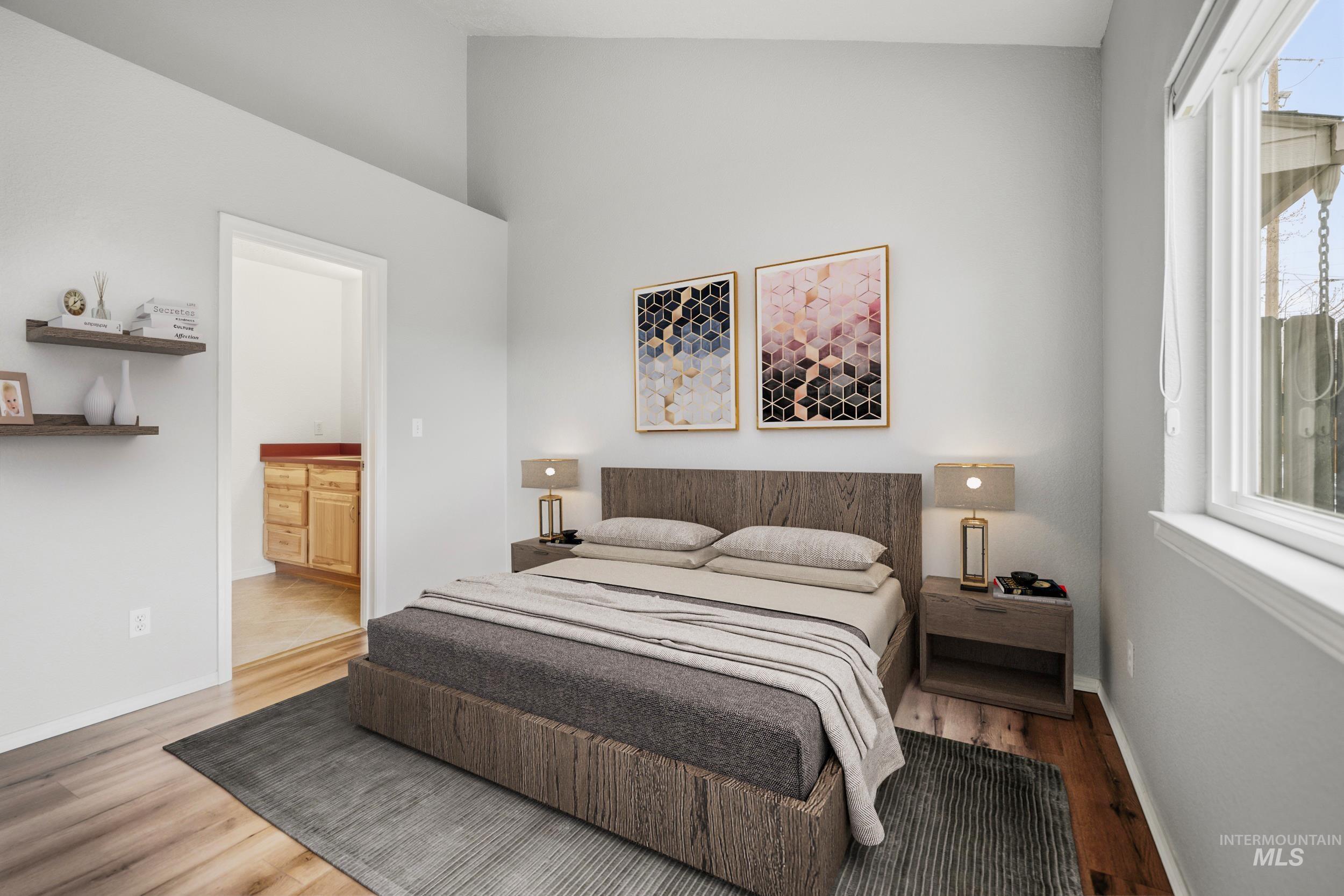 Bedroom with wood finished floors, ensuite bath, and lofted ceiling