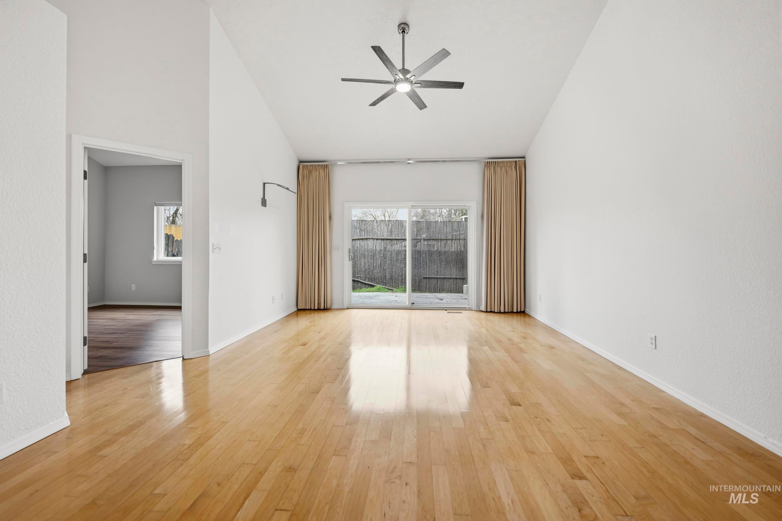 Spare room with ceiling fan, light wood finished floors, and vaulted ceiling