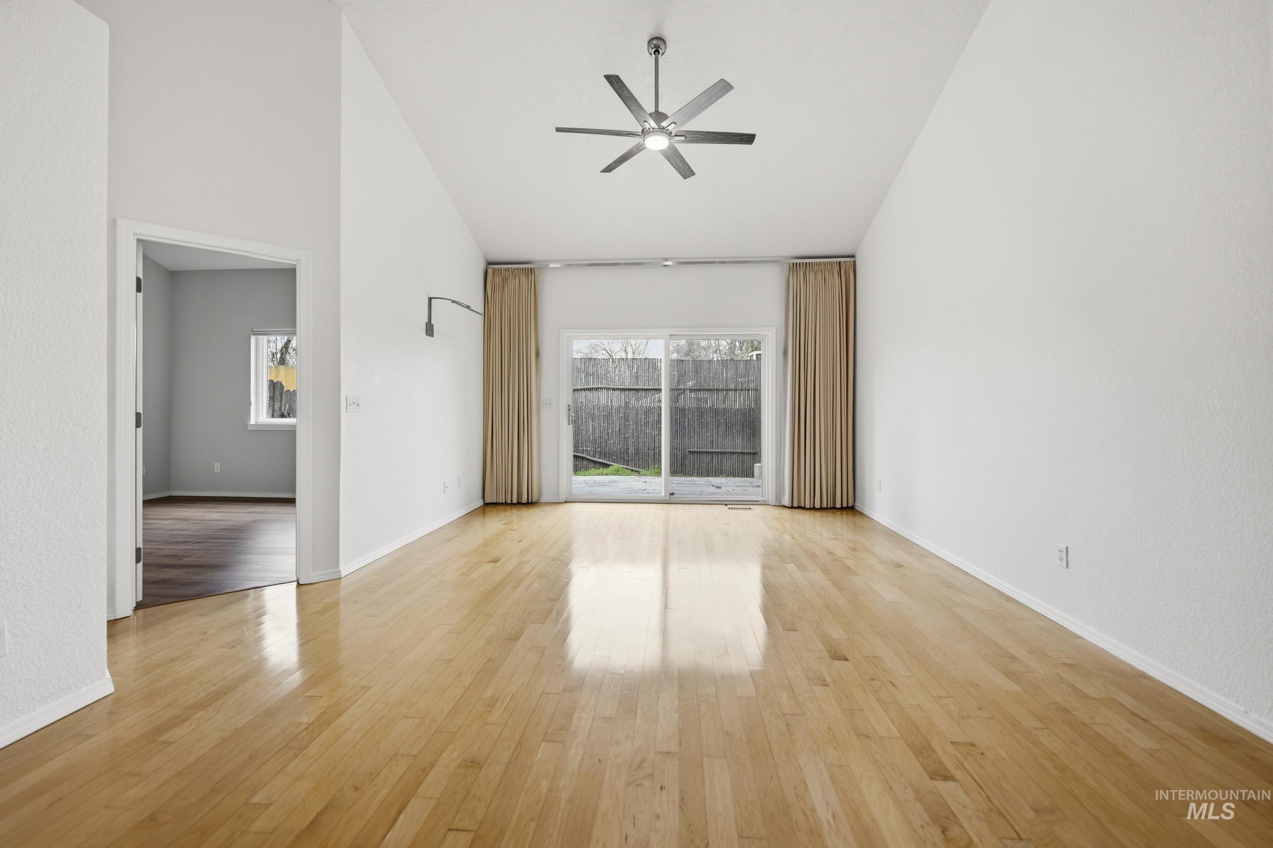 Spare room with ceiling fan, light wood finished floors, and vaulted ceiling