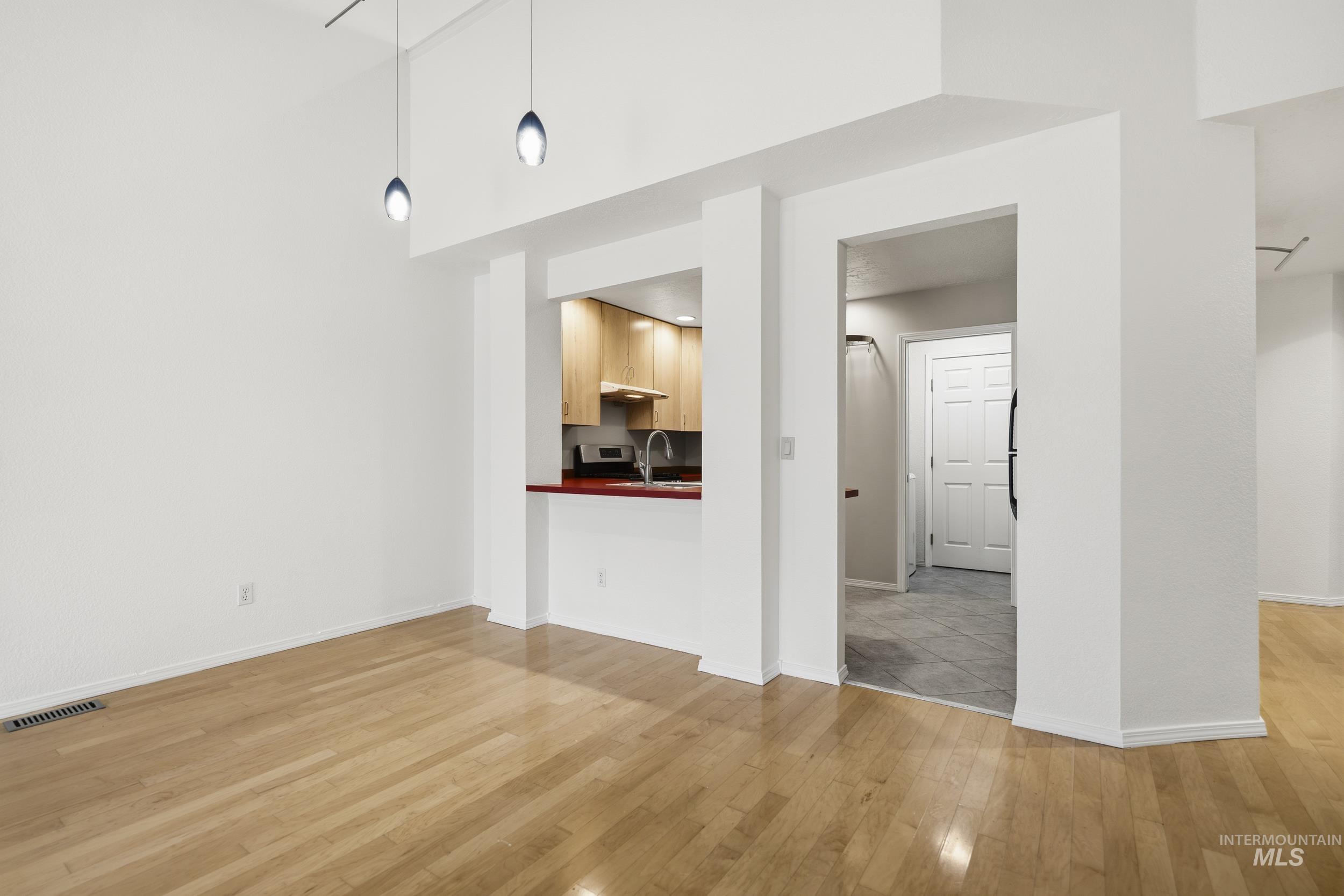 Unfurnished living room with light wood-style floors and a high ceiling