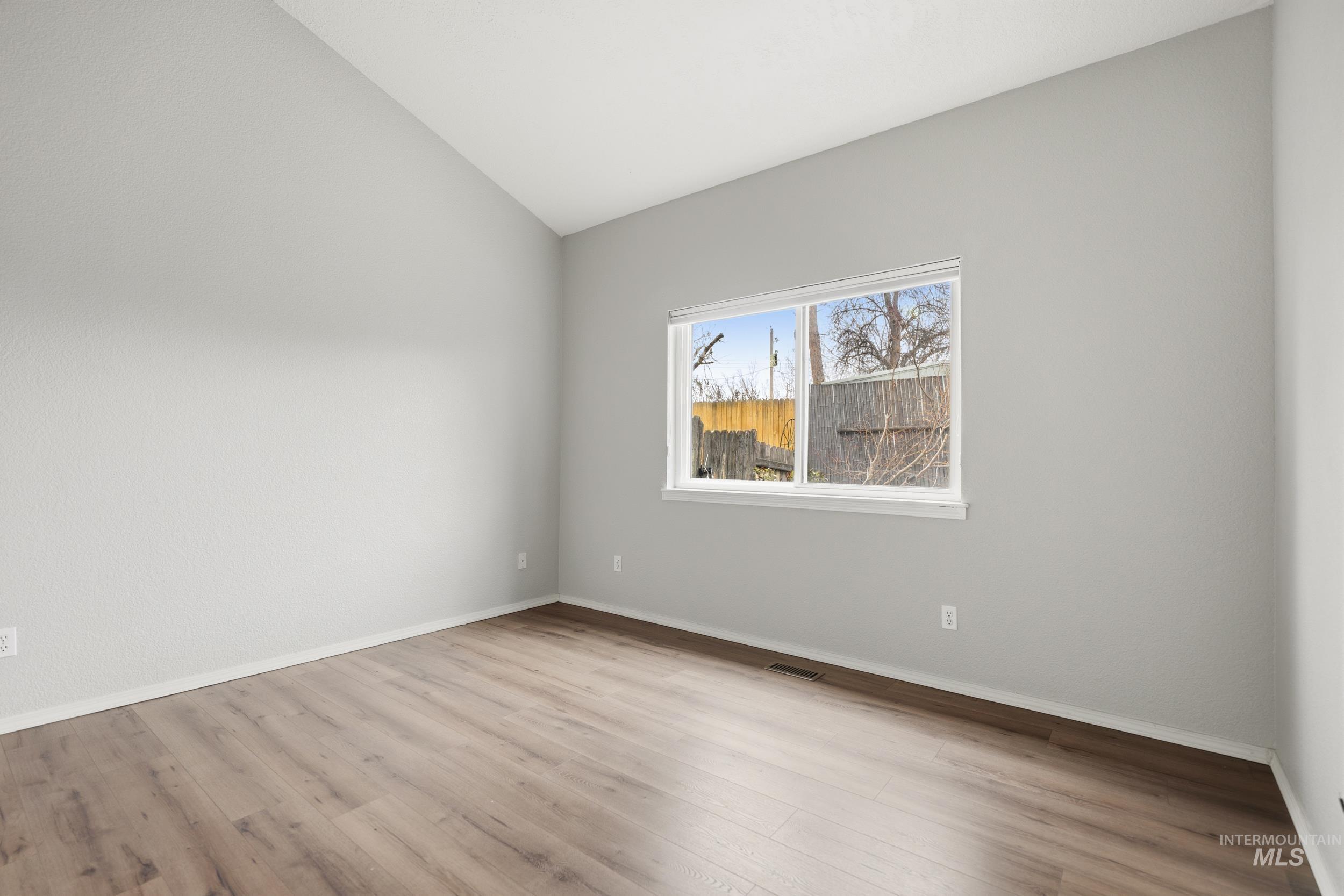 Empty room featuring lofted ceiling and light wood-style flooring