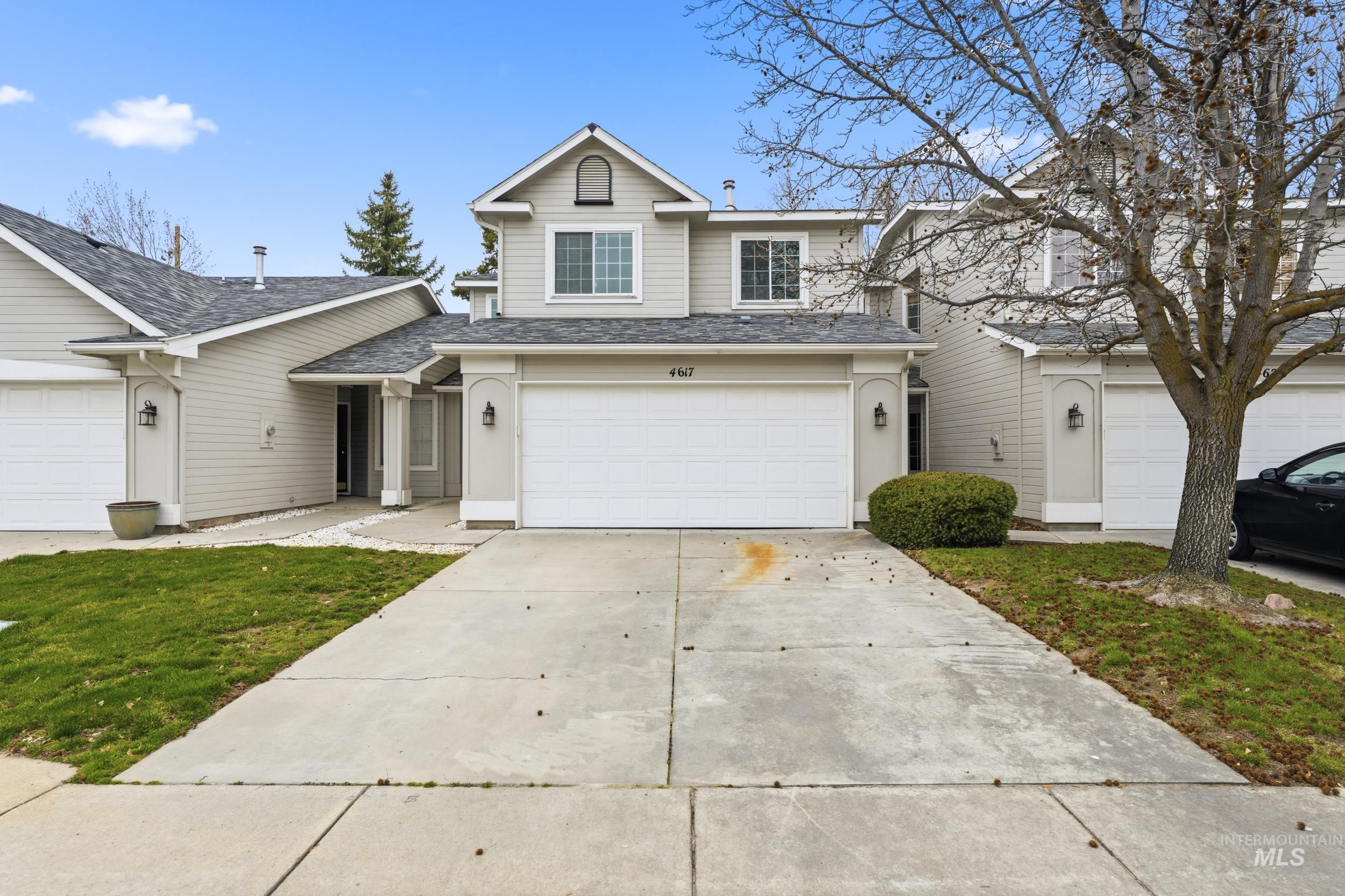 Traditional-style house with an attached garage, driveway, a shingled roof, and a front yard
