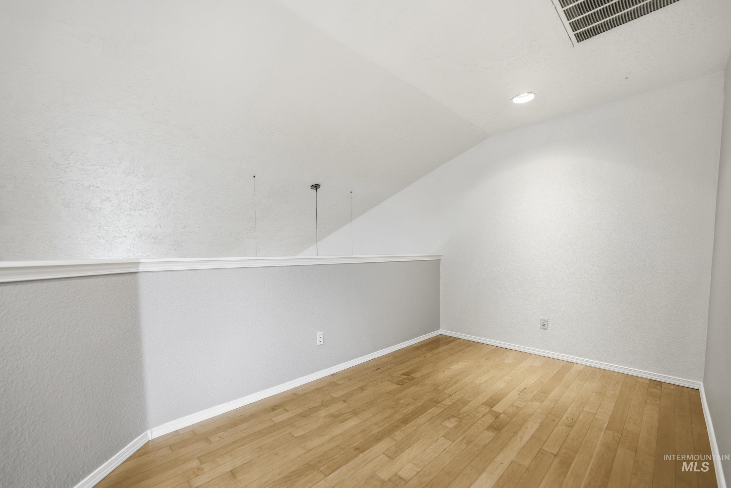 Bonus room with vaulted ceiling, light wood-style flooring, a textured wall, and recessed lighting