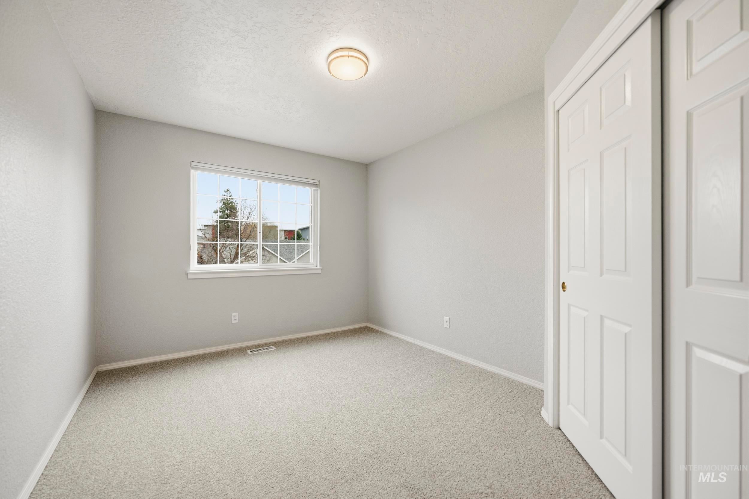 Unfurnished bedroom featuring a closet, light colored carpet, and a textured ceiling