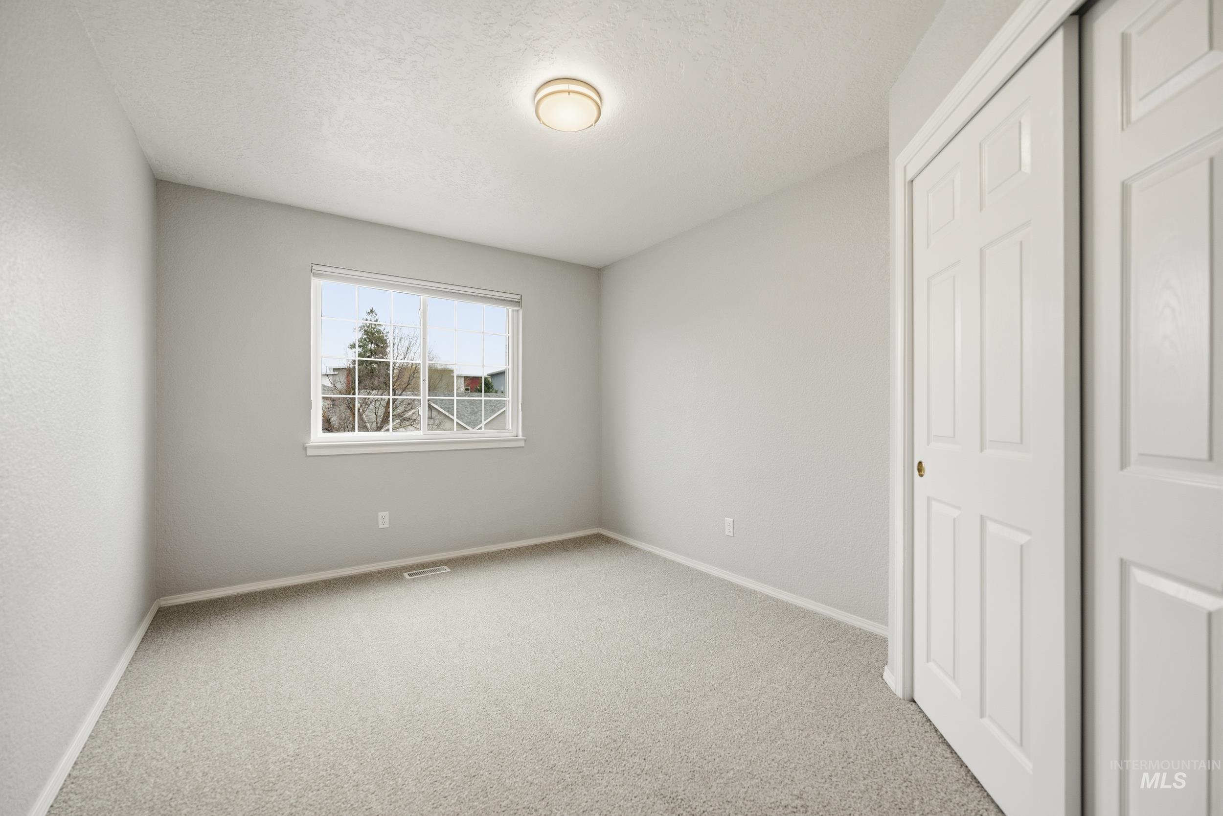 Unfurnished bedroom featuring a closet, light colored carpet, and a textured ceiling