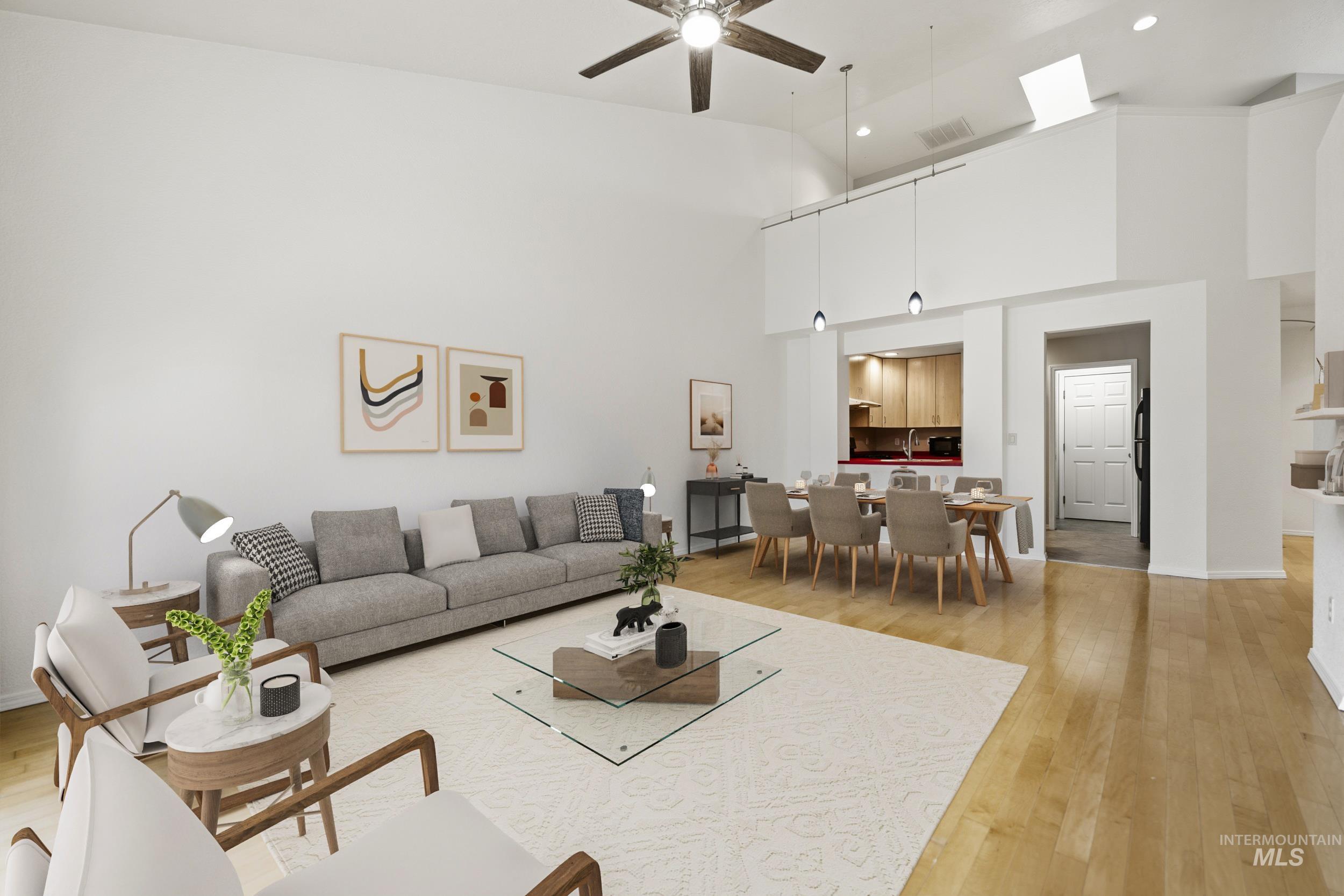 Living area with a ceiling fan, light wood-type flooring, and lofted ceiling