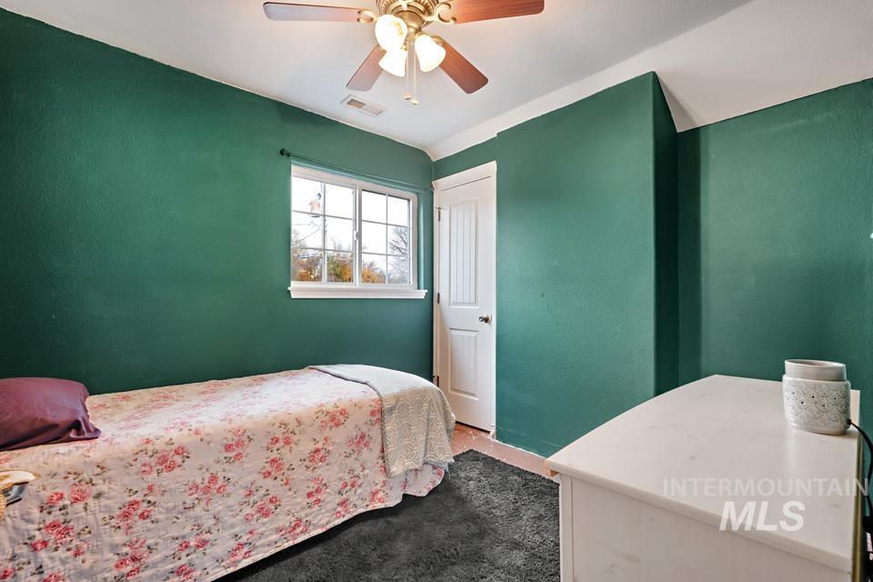 Carpeted bedroom featuring ceiling fan and a textured wall