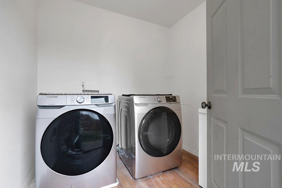 Laundry area featuring wood finished floors and washing machine and clothes dryer
