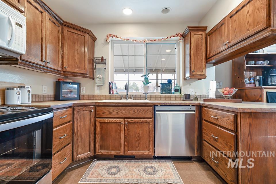 Kitchen featuring appliances with stainless steel finishes, brown cabinets, light countertops, a peninsula, and recessed lighting