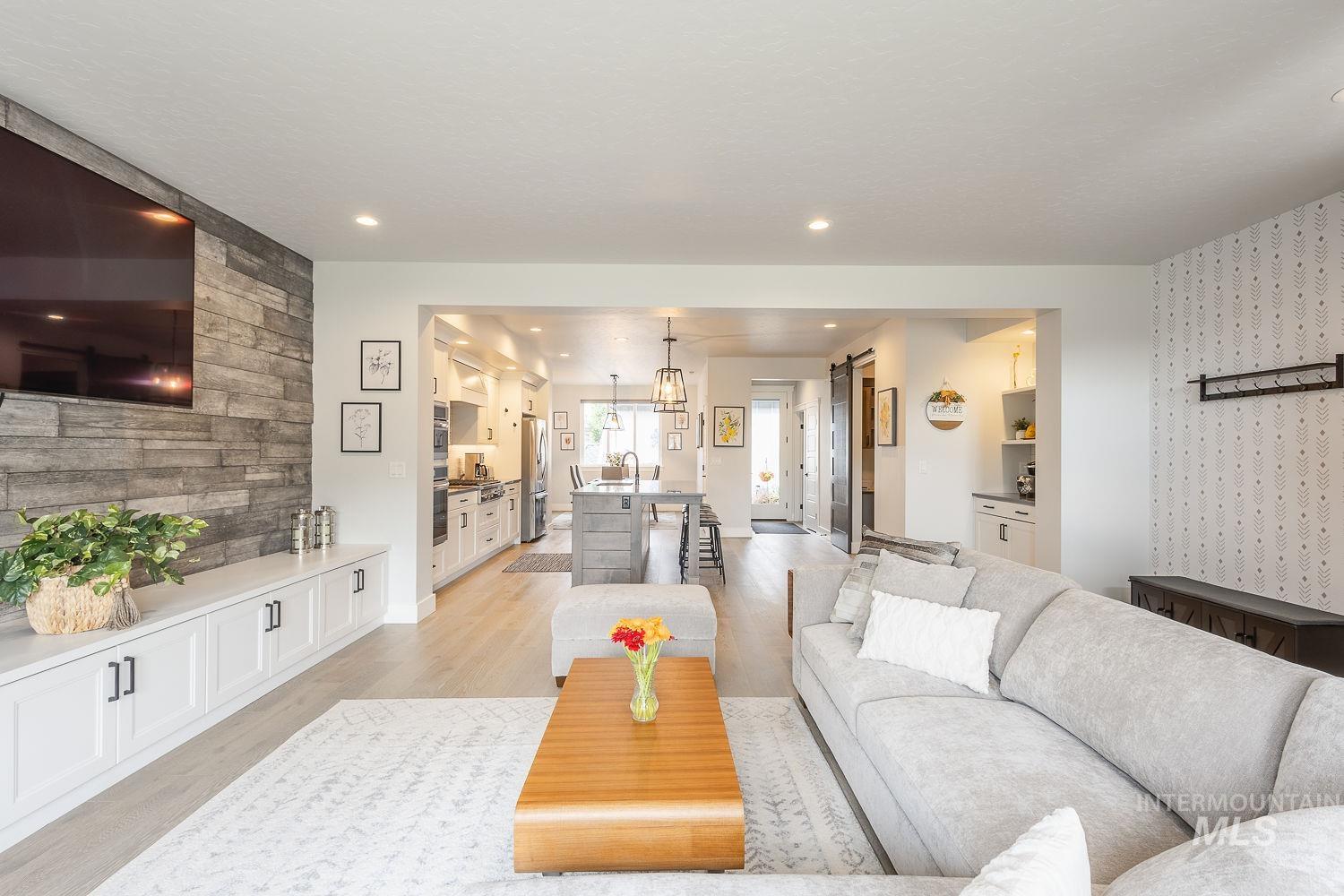 Living area with an accent wall, light wood-type flooring, a barn door, recessed lighting, and wallpapered walls