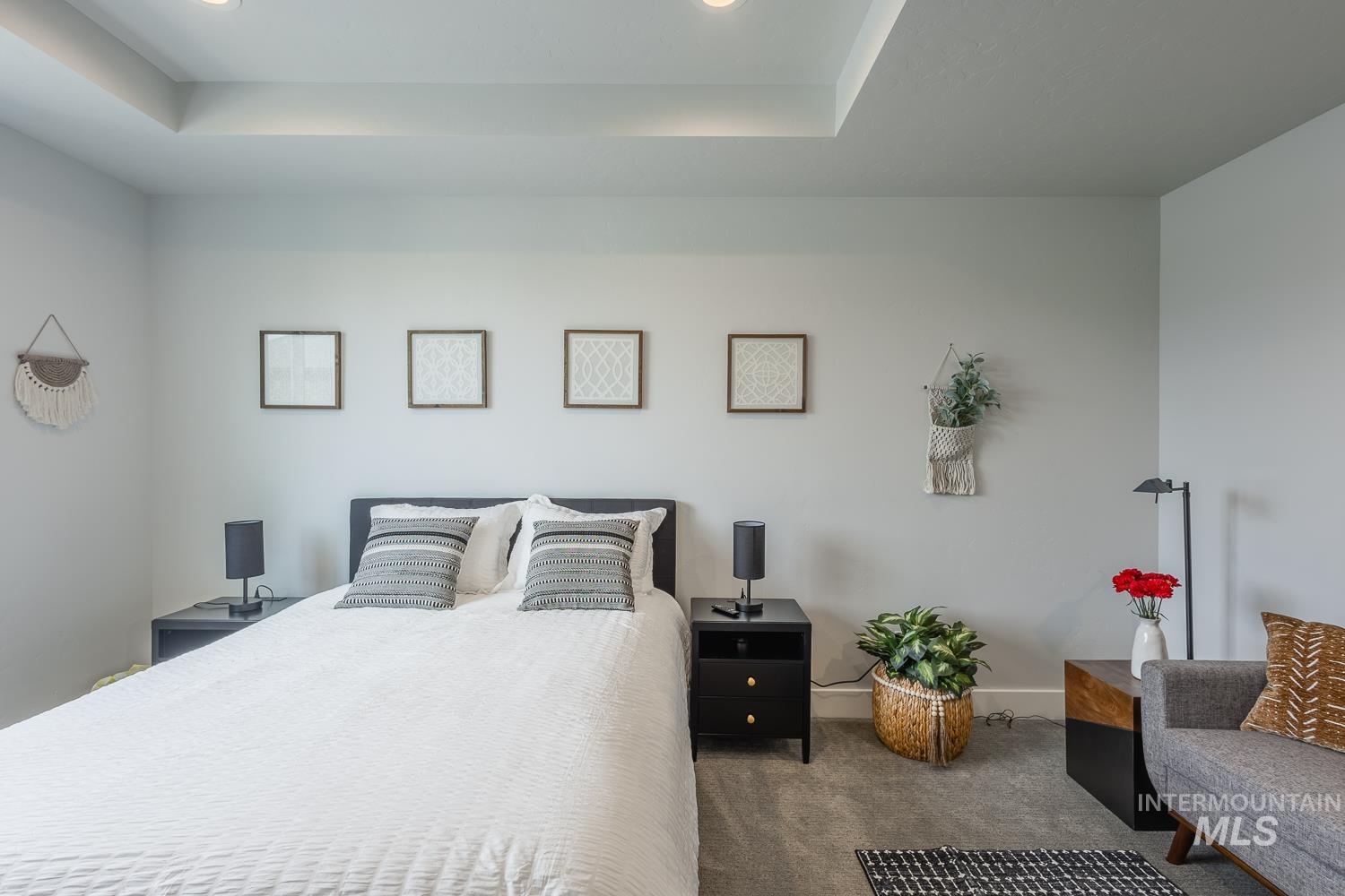 Bedroom featuring a raised ceiling, dark carpet, and recessed lighting