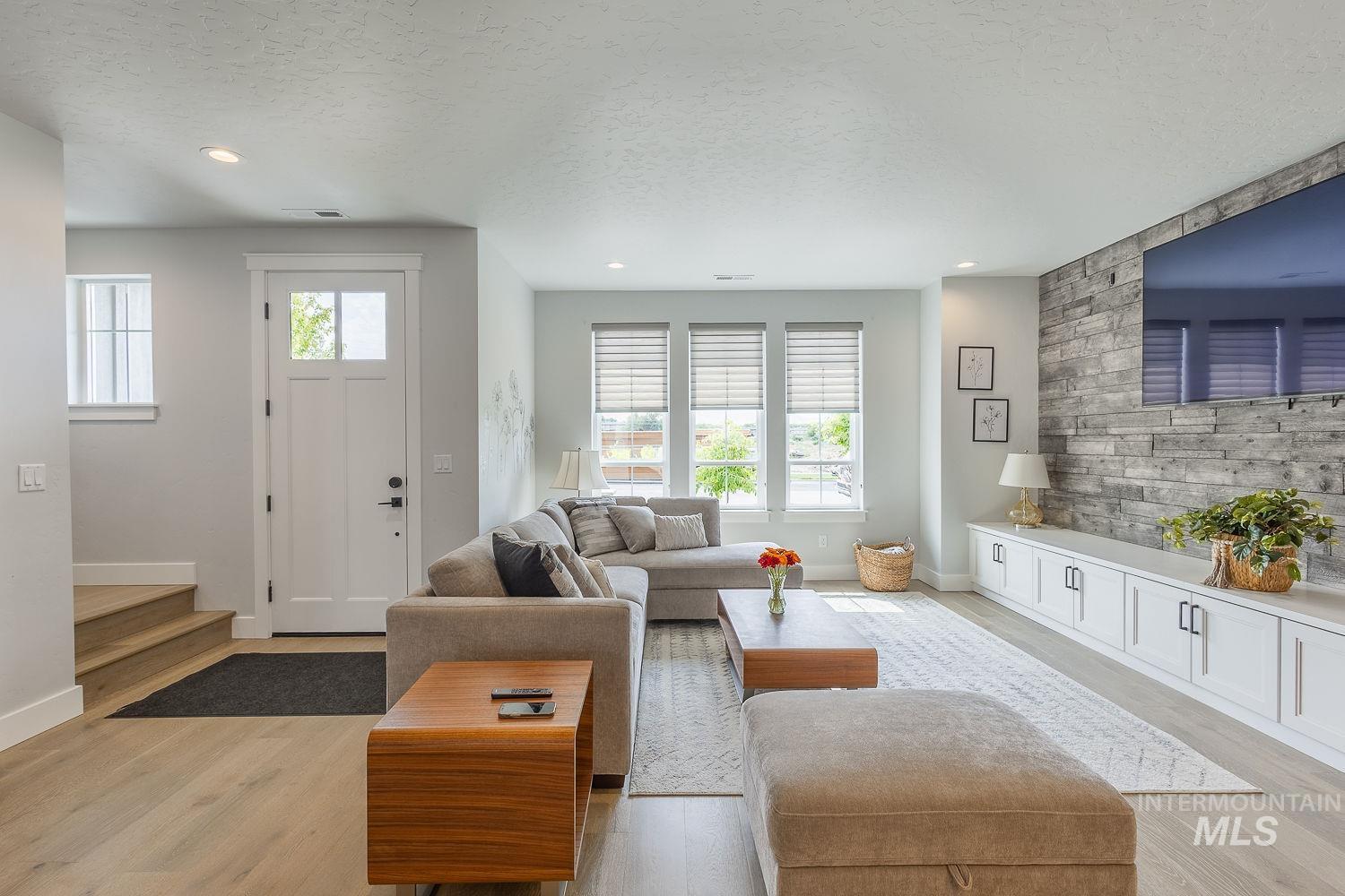 Living area with a textured ceiling, light wood finished floors, and recessed lighting