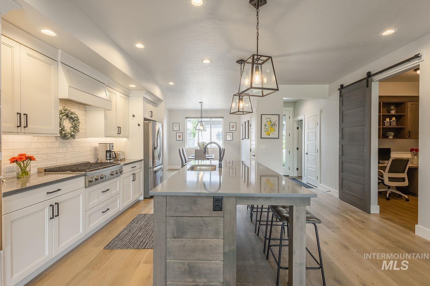 Kitchen with pendant lighting, a breakfast bar area, a center island with sink, a desk, and recessed lighting