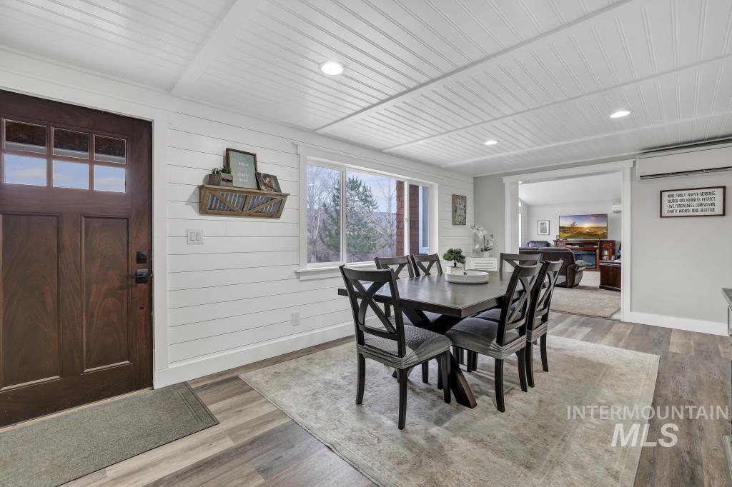 Dining room featuring light wood finished floors, recessed lighting, an AC wall unit, and wood walls