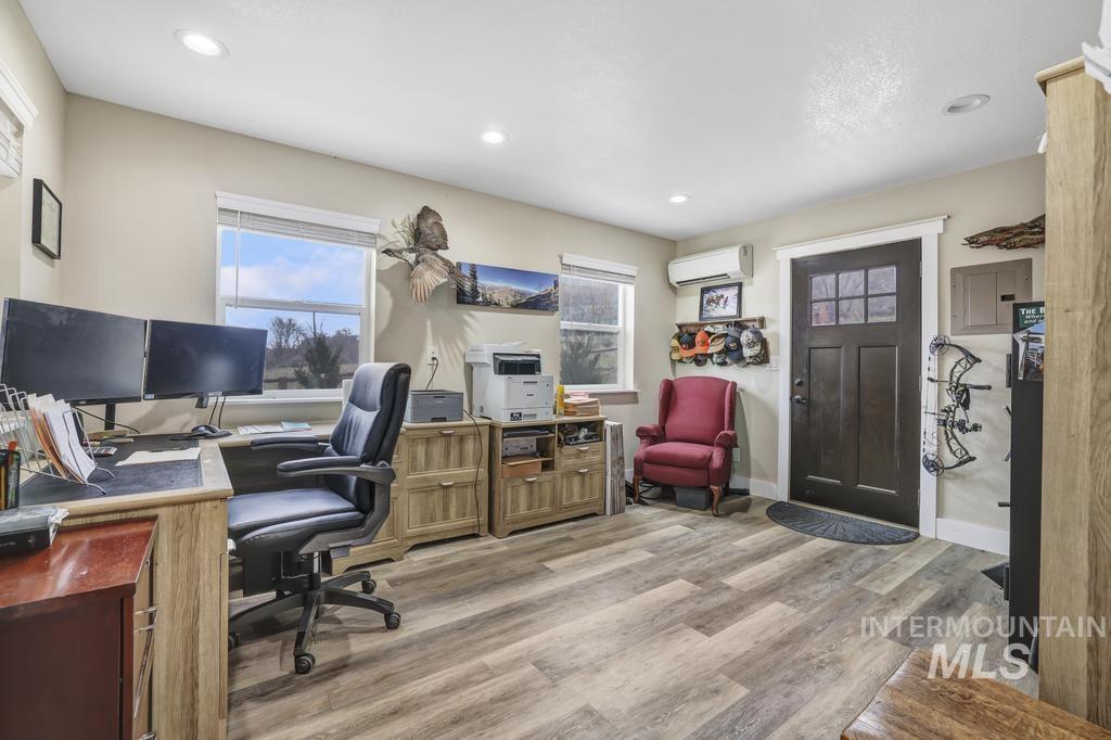 Home office with light wood-style floors, electric panel, and recessed lighting