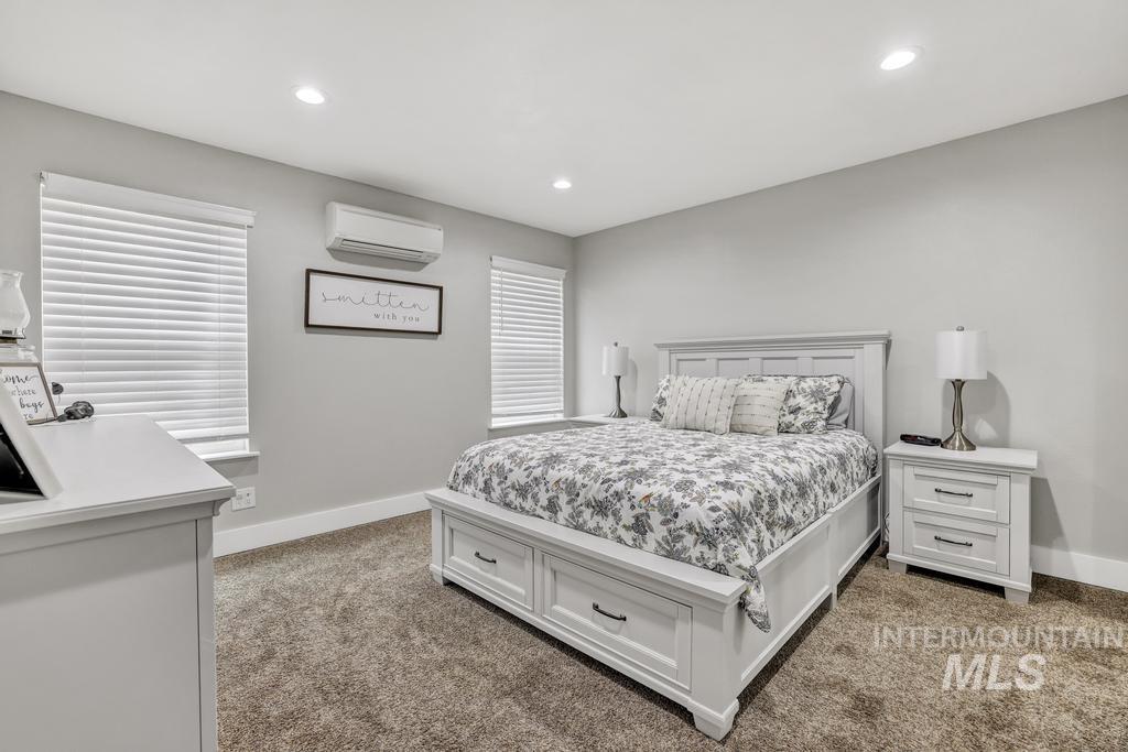 Bedroom featuring an AC wall unit, light colored carpet, and recessed lighting