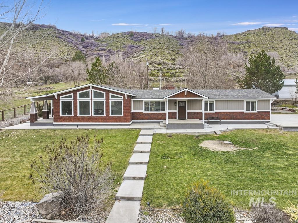 View of front of home featuring a mountain view, a front lawn, covered porch, and brick siding