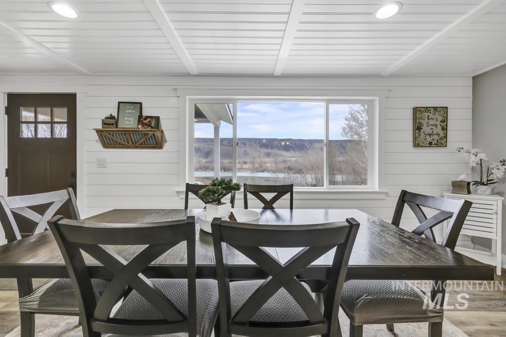 Dining space featuring wooden walls, light wood-style floors, and beam ceiling