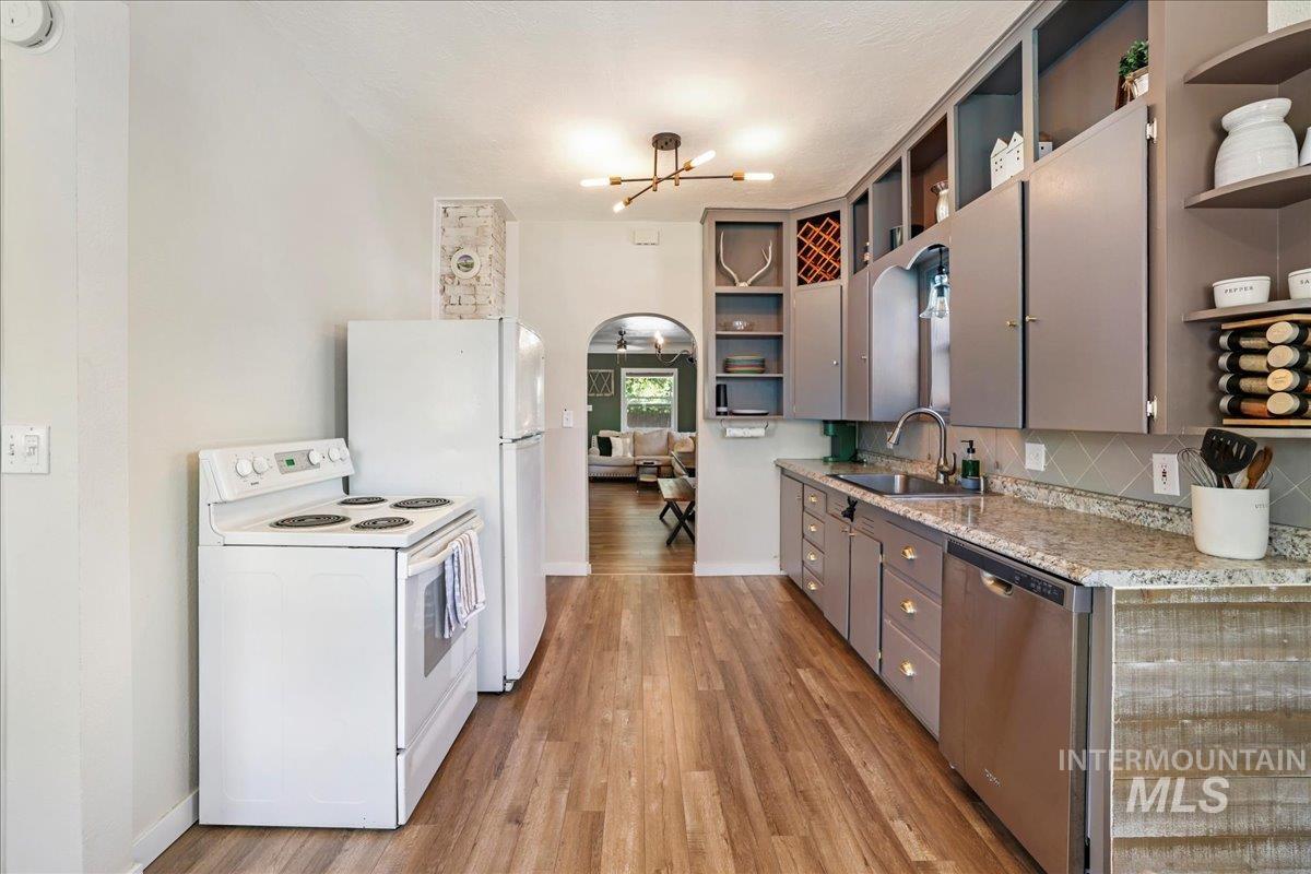 Kitchen featuring open shelves, white appliances, a chandelier, and light wood-style floors