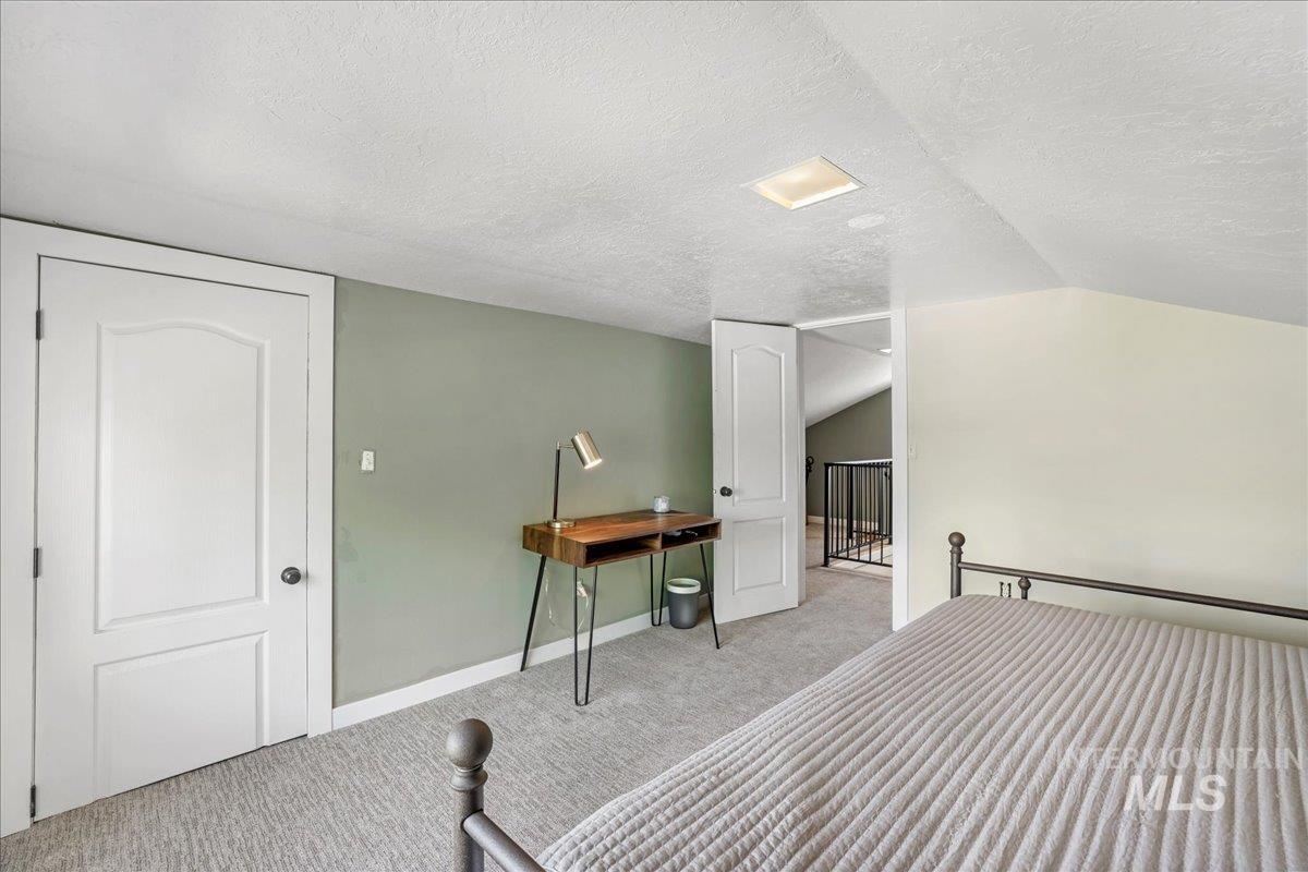 Bedroom featuring a textured ceiling, carpet floors, and lofted ceiling