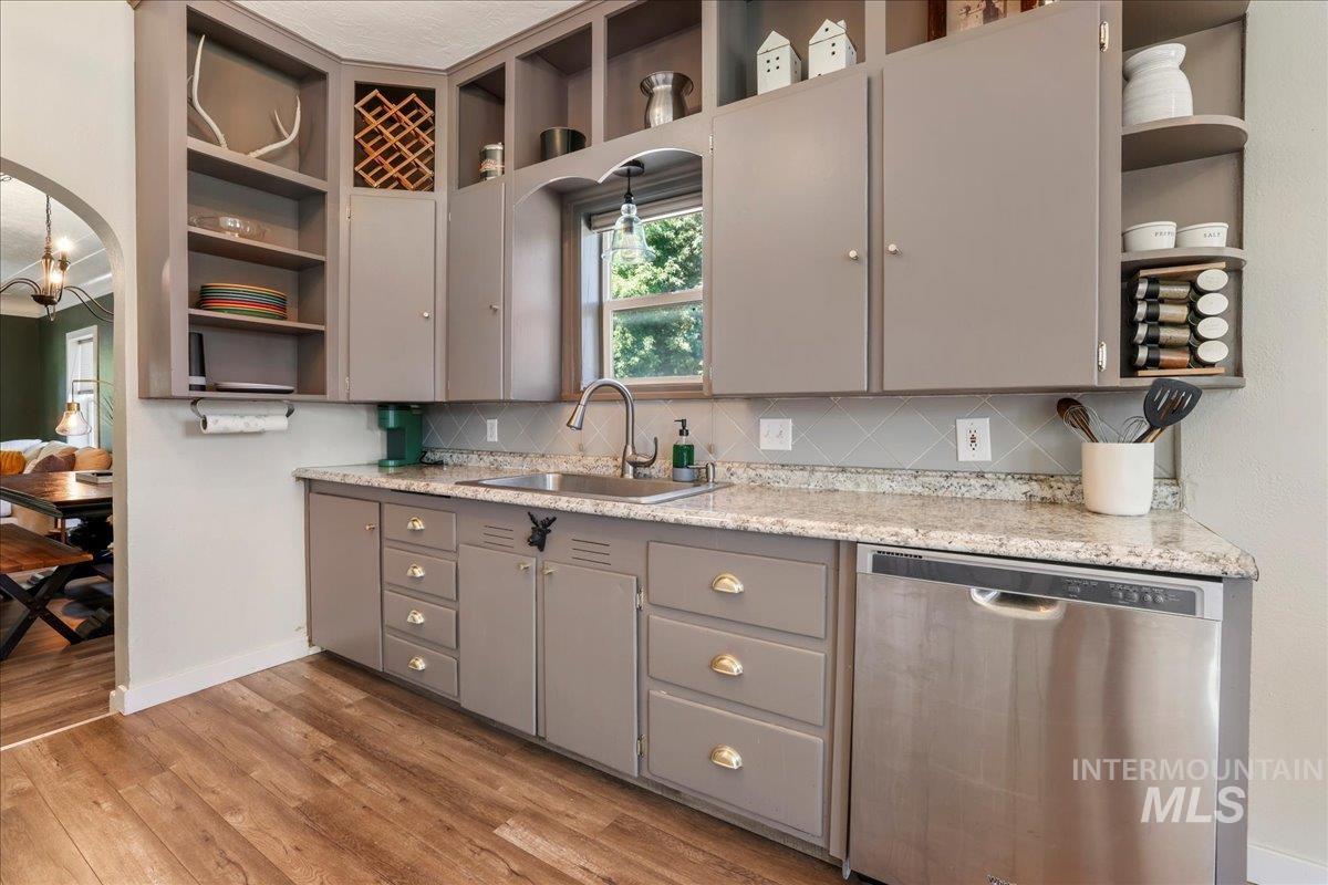 Kitchen with open shelves, dishwasher, gray cabinetry, backsplash, and light wood-style flooring