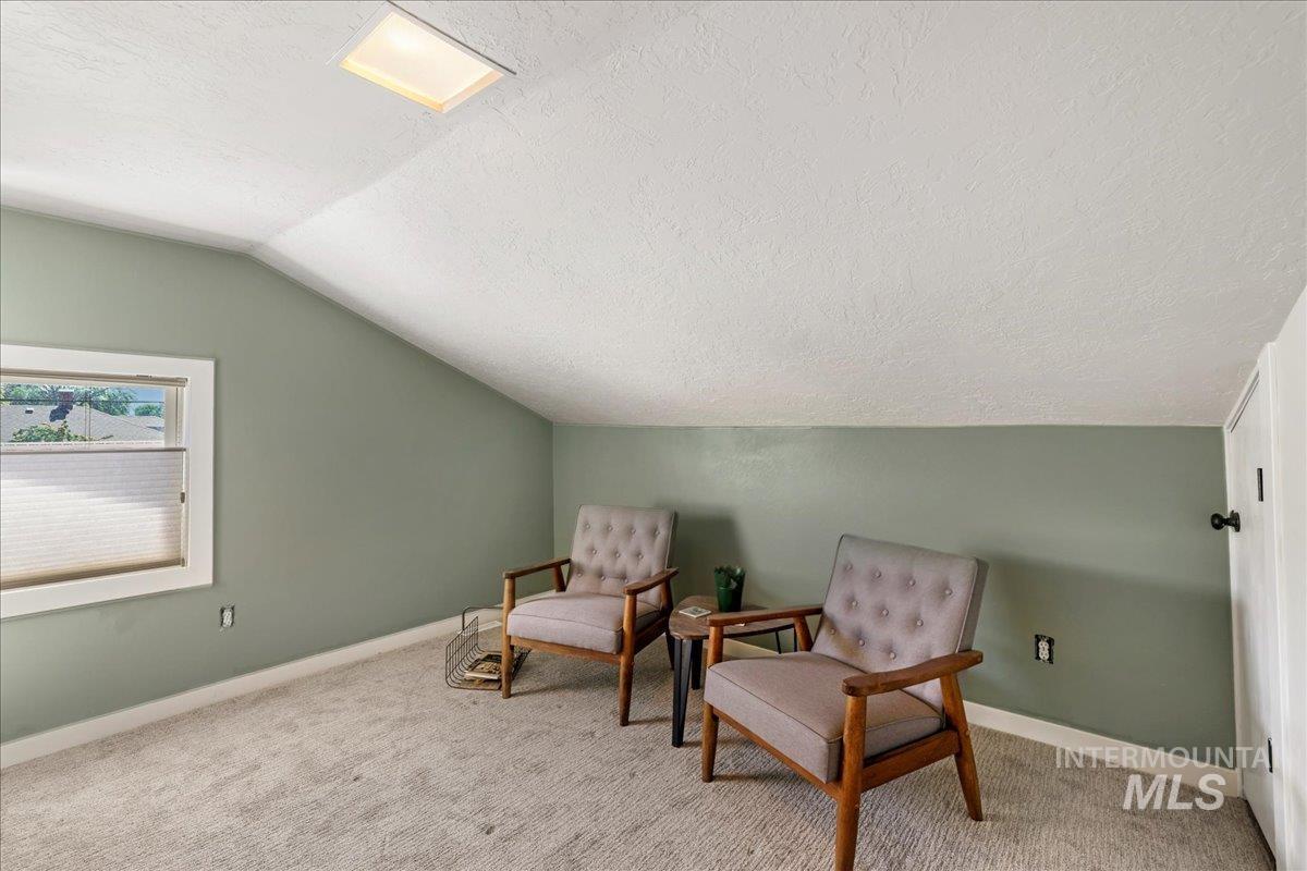 Sitting room with lofted ceiling, a textured ceiling, and carpet