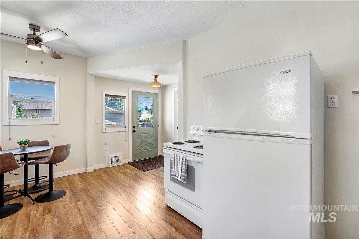 Kitchen featuring white appliances, light wood-style floors, and ceiling fan