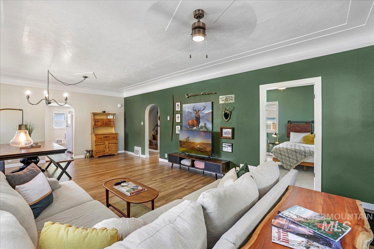 Living area featuring arched walkways, wood finished floors, ornamental molding, ceiling fan, and a textured ceiling
