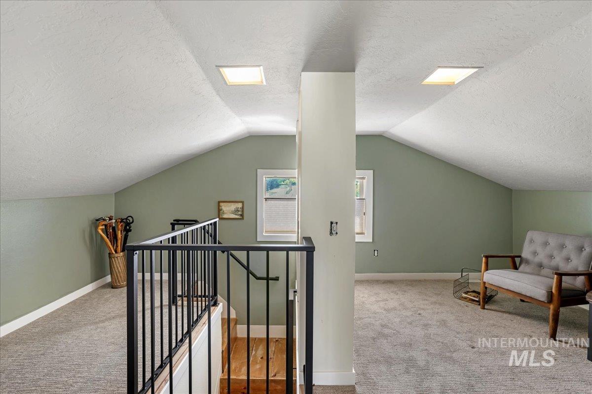 Additional living space with a textured ceiling, carpet flooring, and lofted ceiling