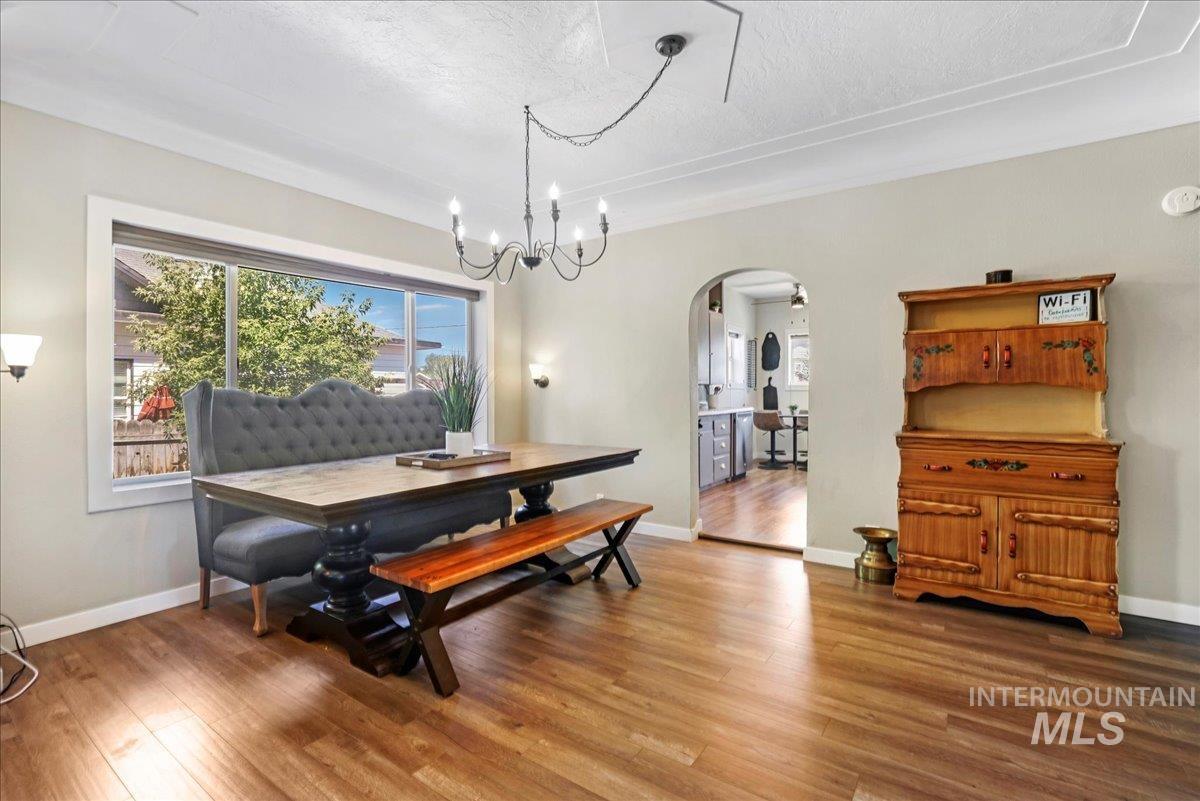 Dining space featuring arched walkways, wood finished floors, a chandelier, and a textured ceiling
