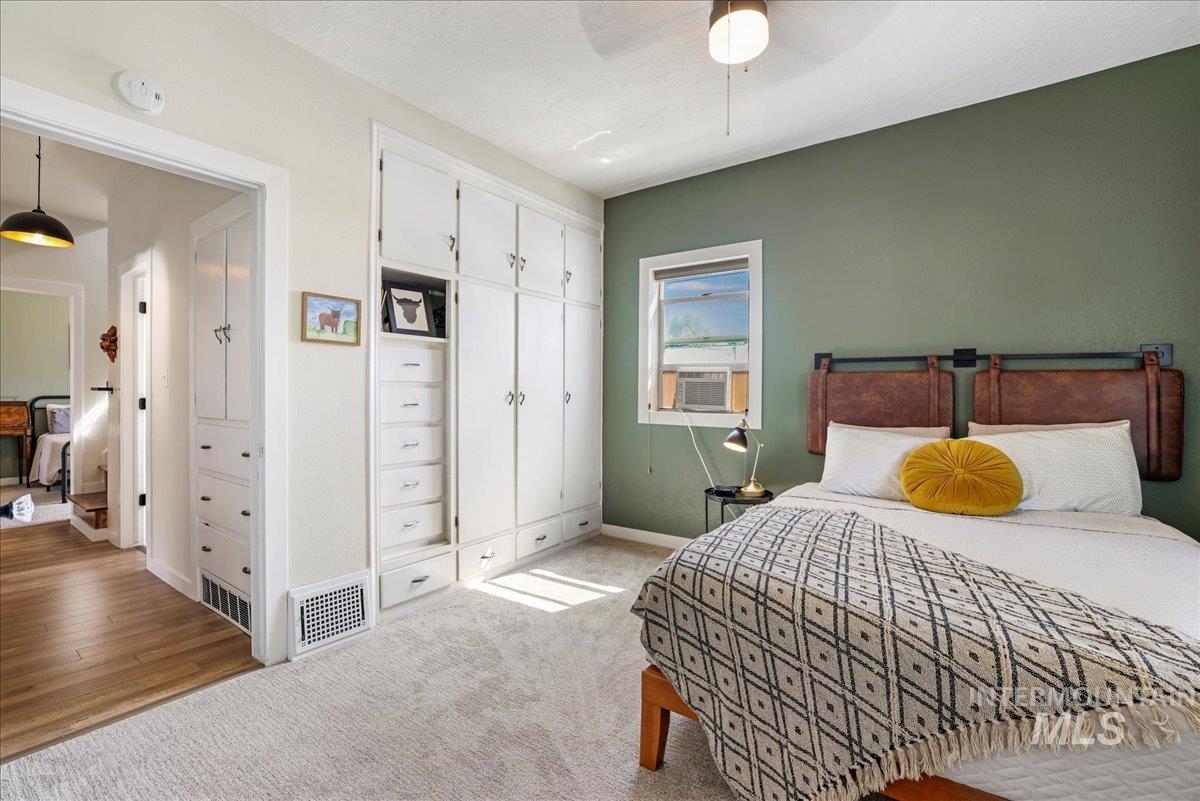 Bedroom with a closet, ceiling fan, cooling unit, light wood-style flooring, and light colored carpet