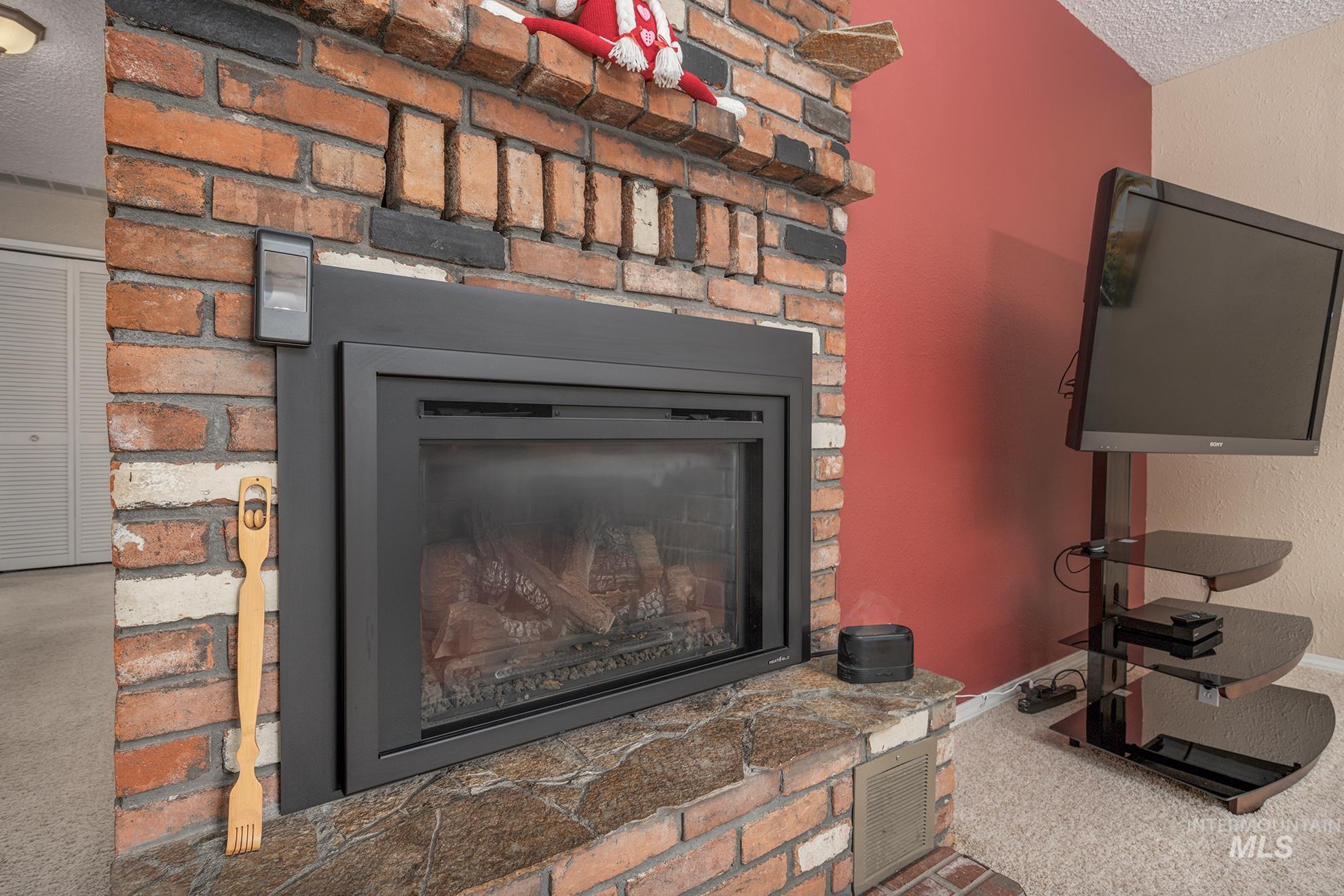 Detailed view of carpet, a glass covered fireplace, a textured ceiling, and a textured wall
