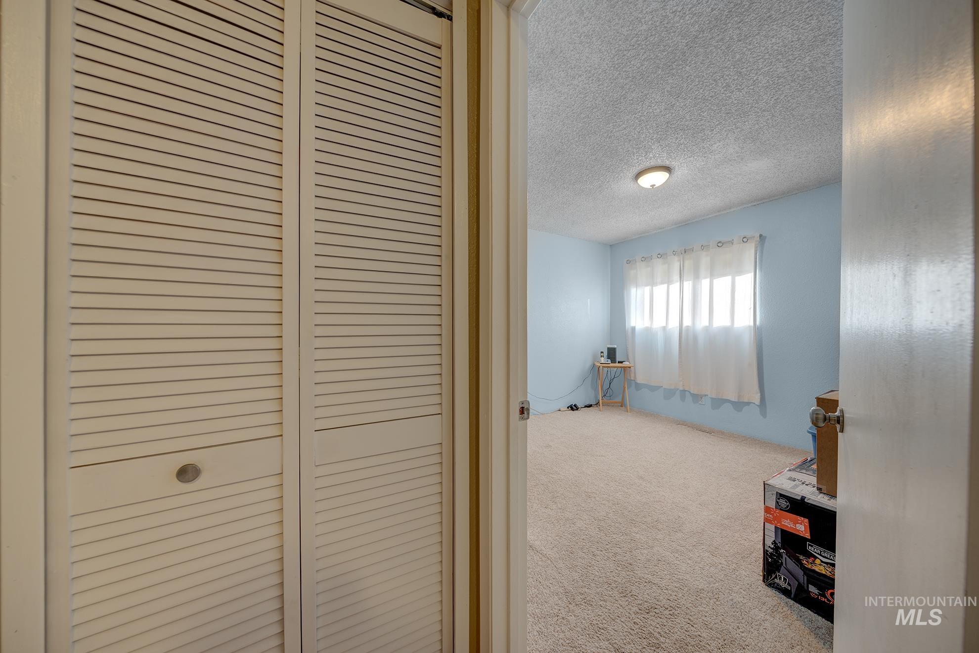 Hall featuring a textured ceiling and carpet flooring