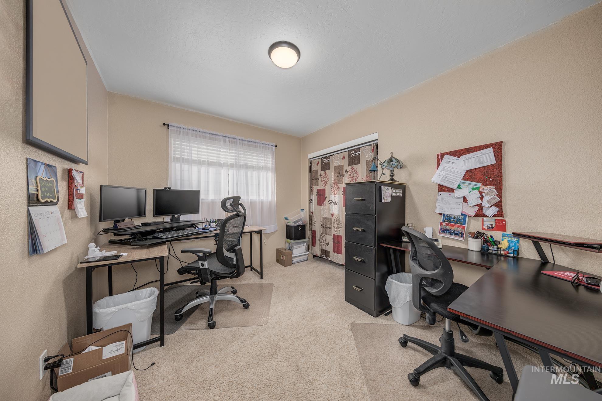 Office area with light carpet and a textured wall