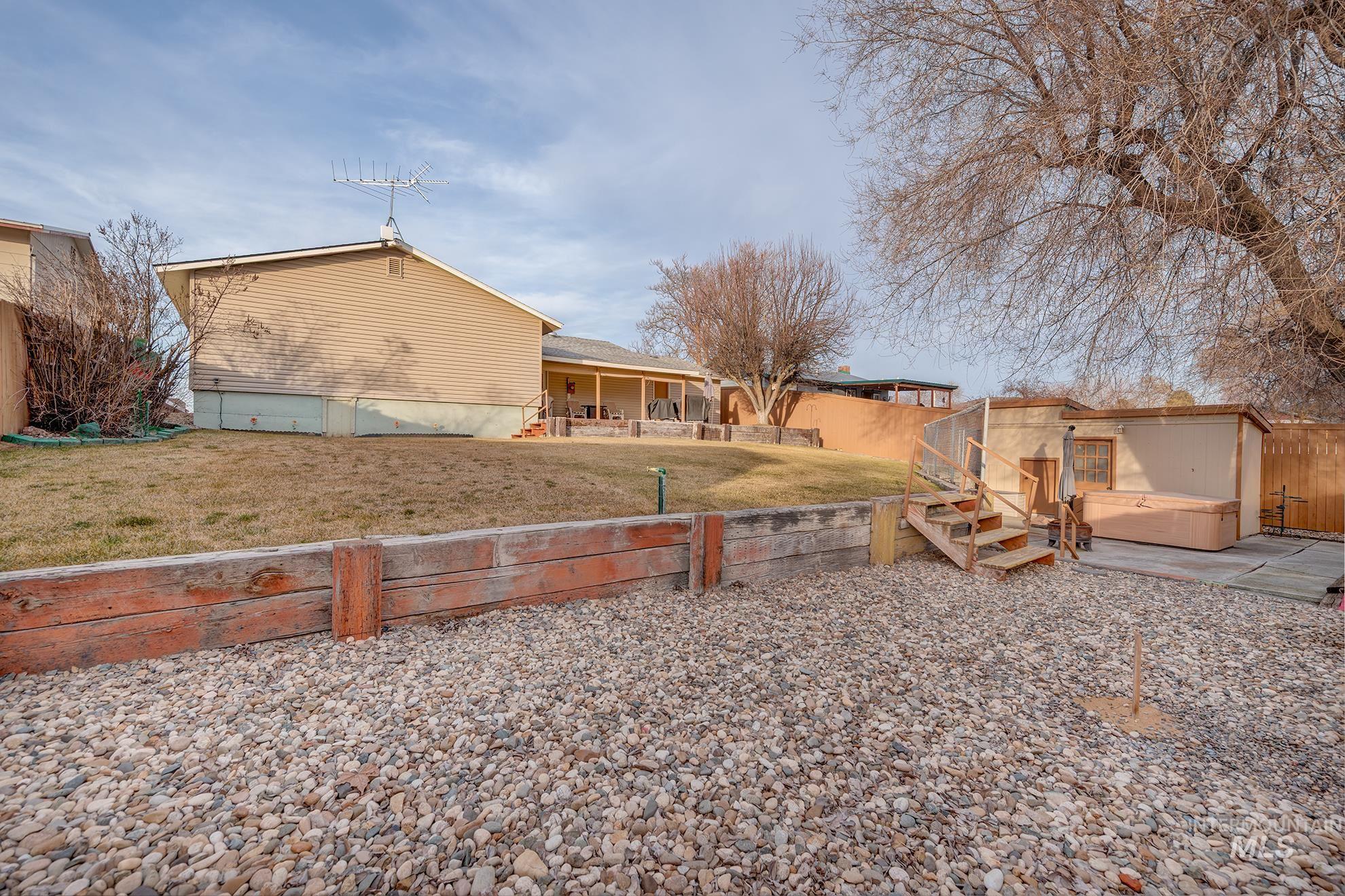 Fenced backyard with a hot tub and an outbuilding