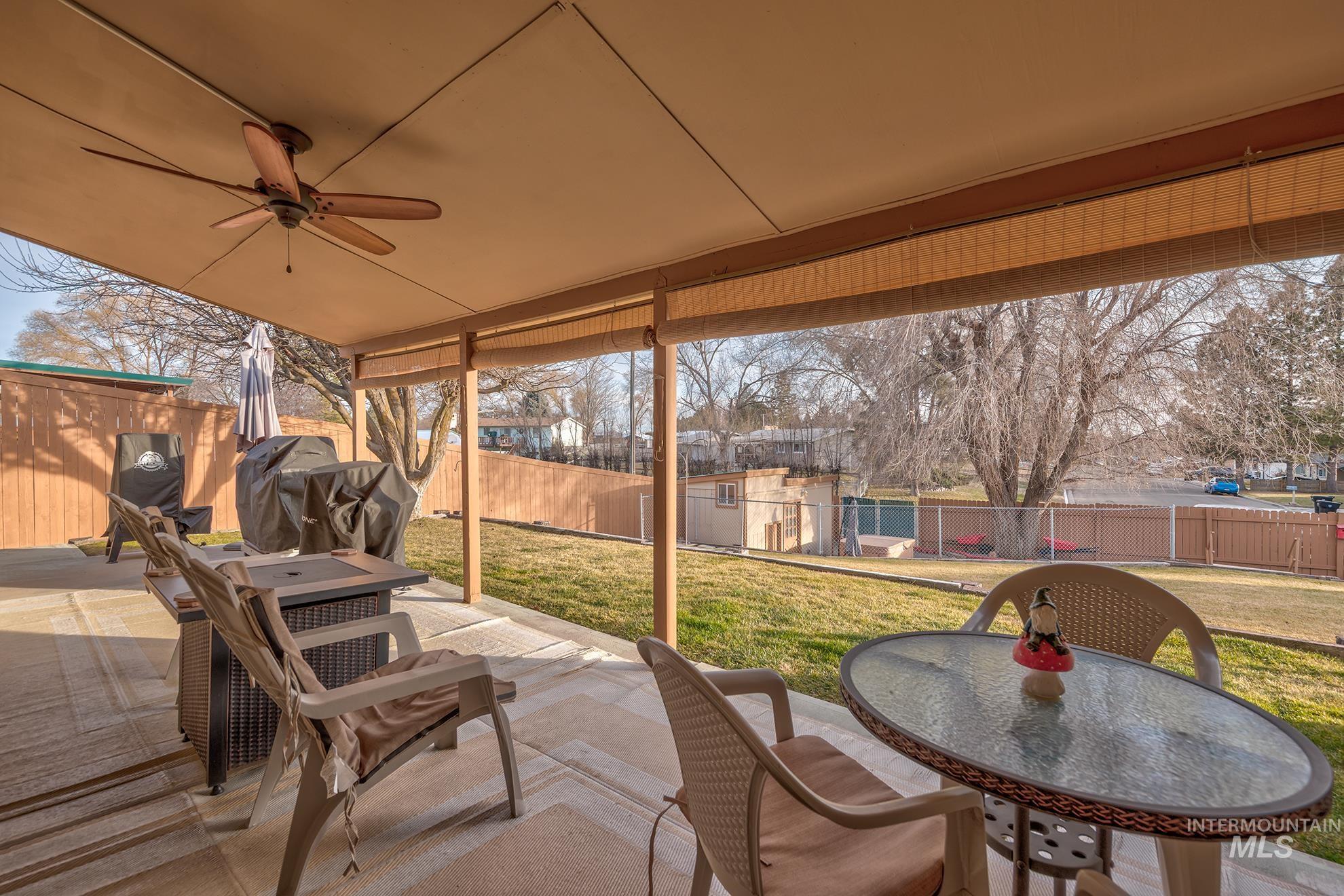 Fenced backyard featuring a patio, outdoor dining area, a ceiling fan, and a shed