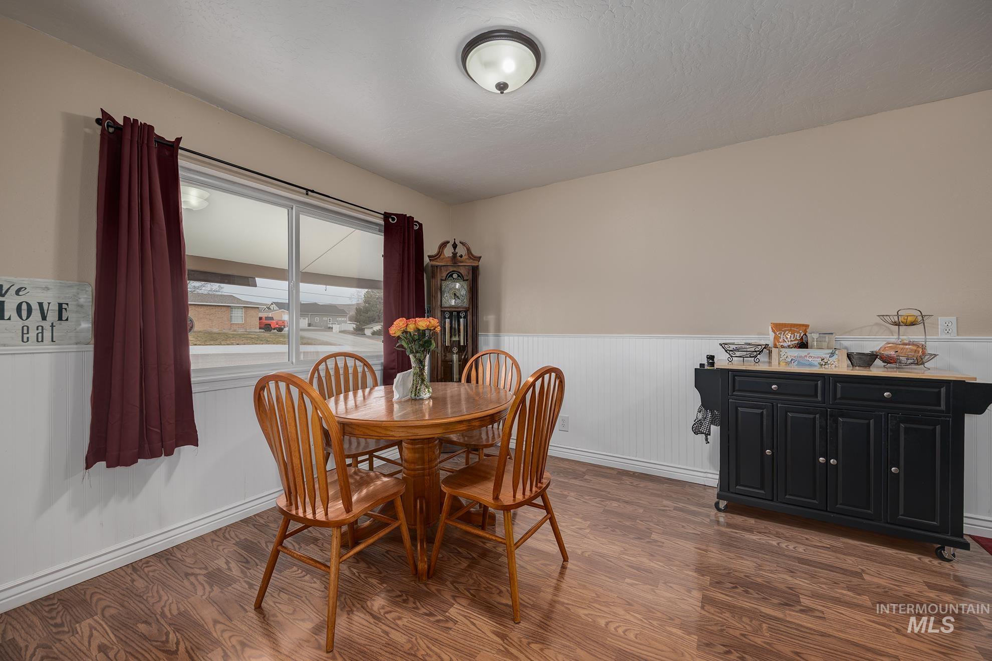 Dining space featuring dark wood-style flooring and a wainscoted wall