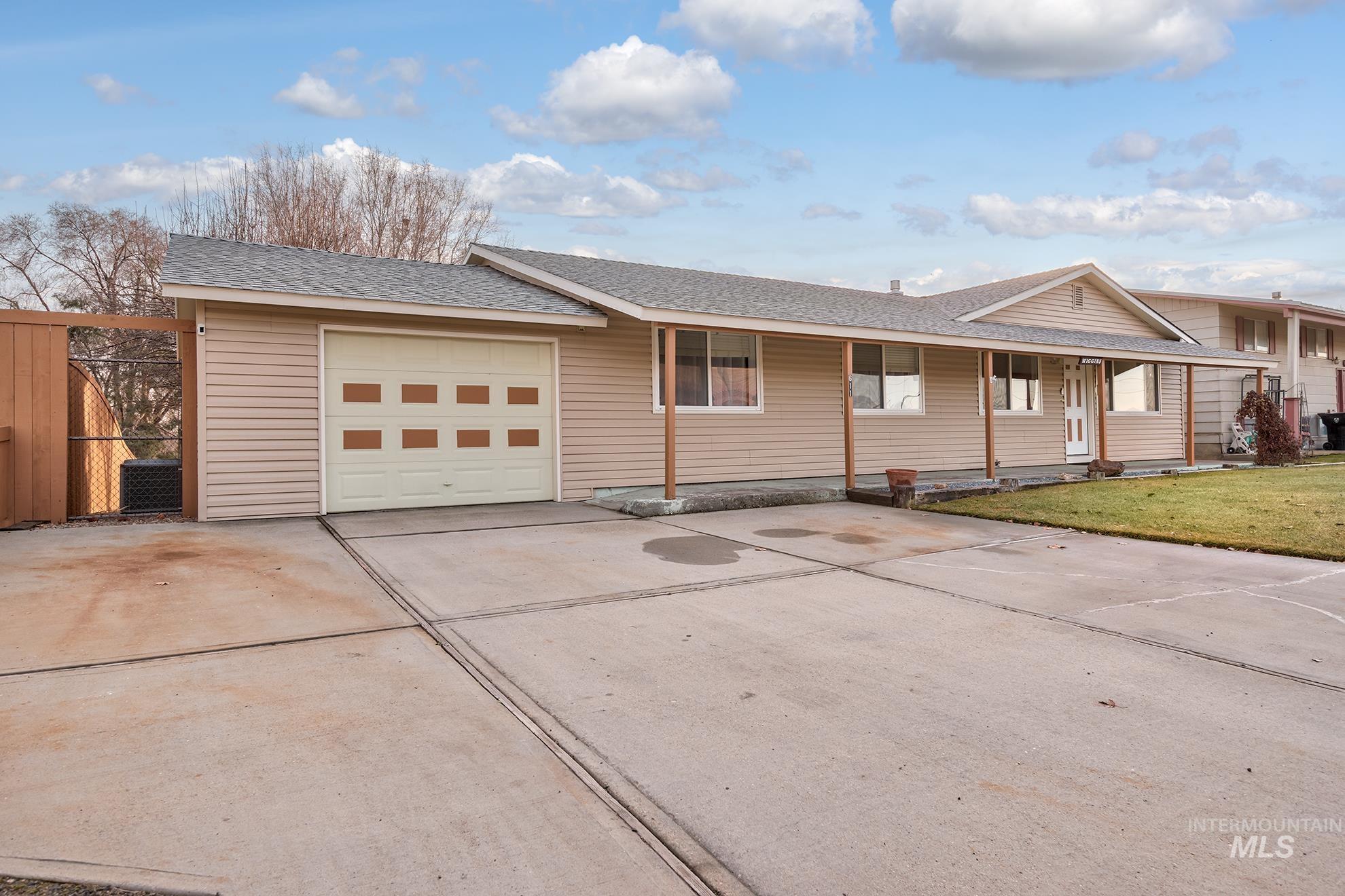 Ranch-style house featuring roof with shingles, concrete driveway, covered porch, and an attached garage