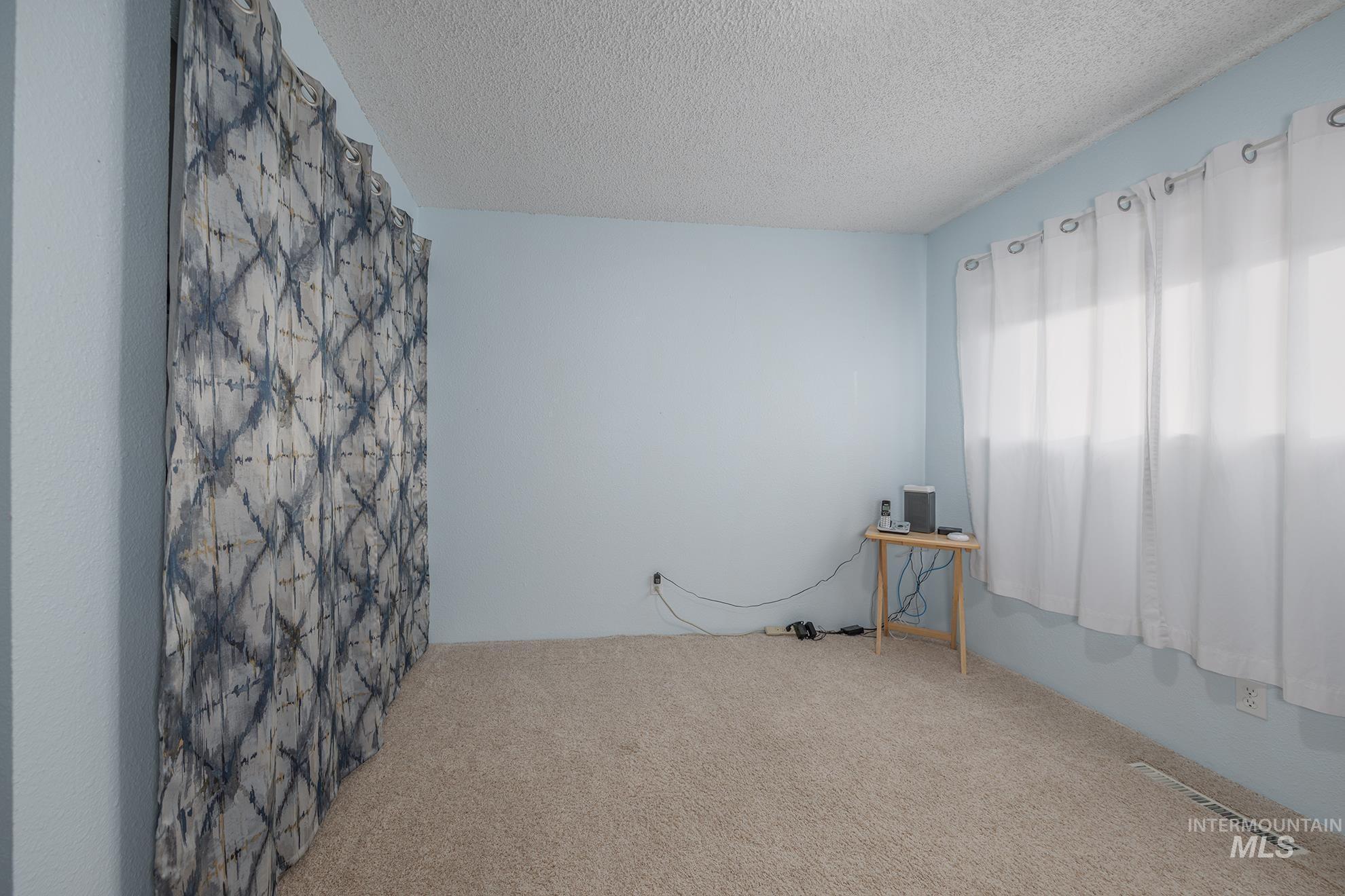 Carpeted spare room with a textured ceiling