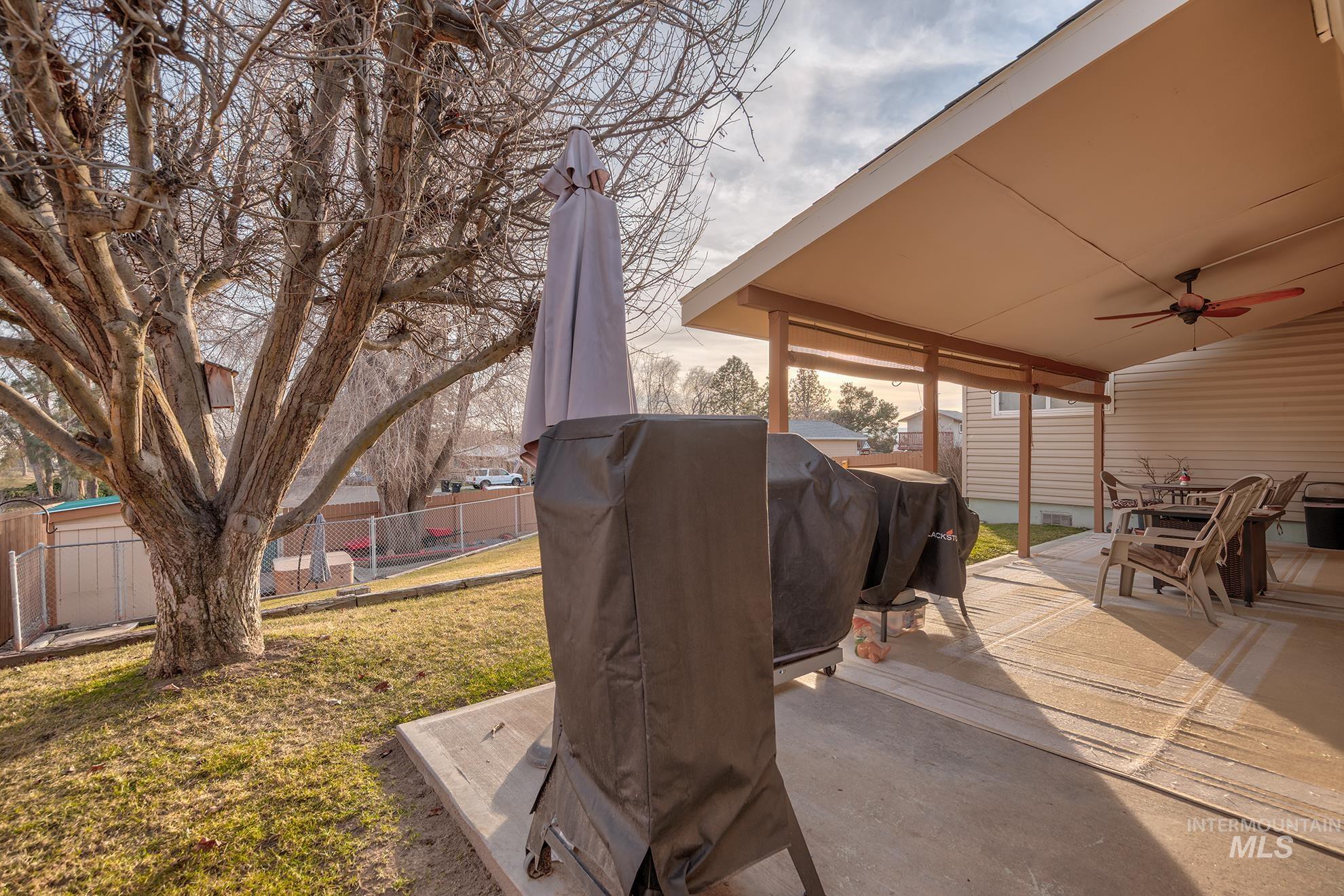 Fenced backyard with a ceiling fan, grilling area, a patio, and outdoor dining space