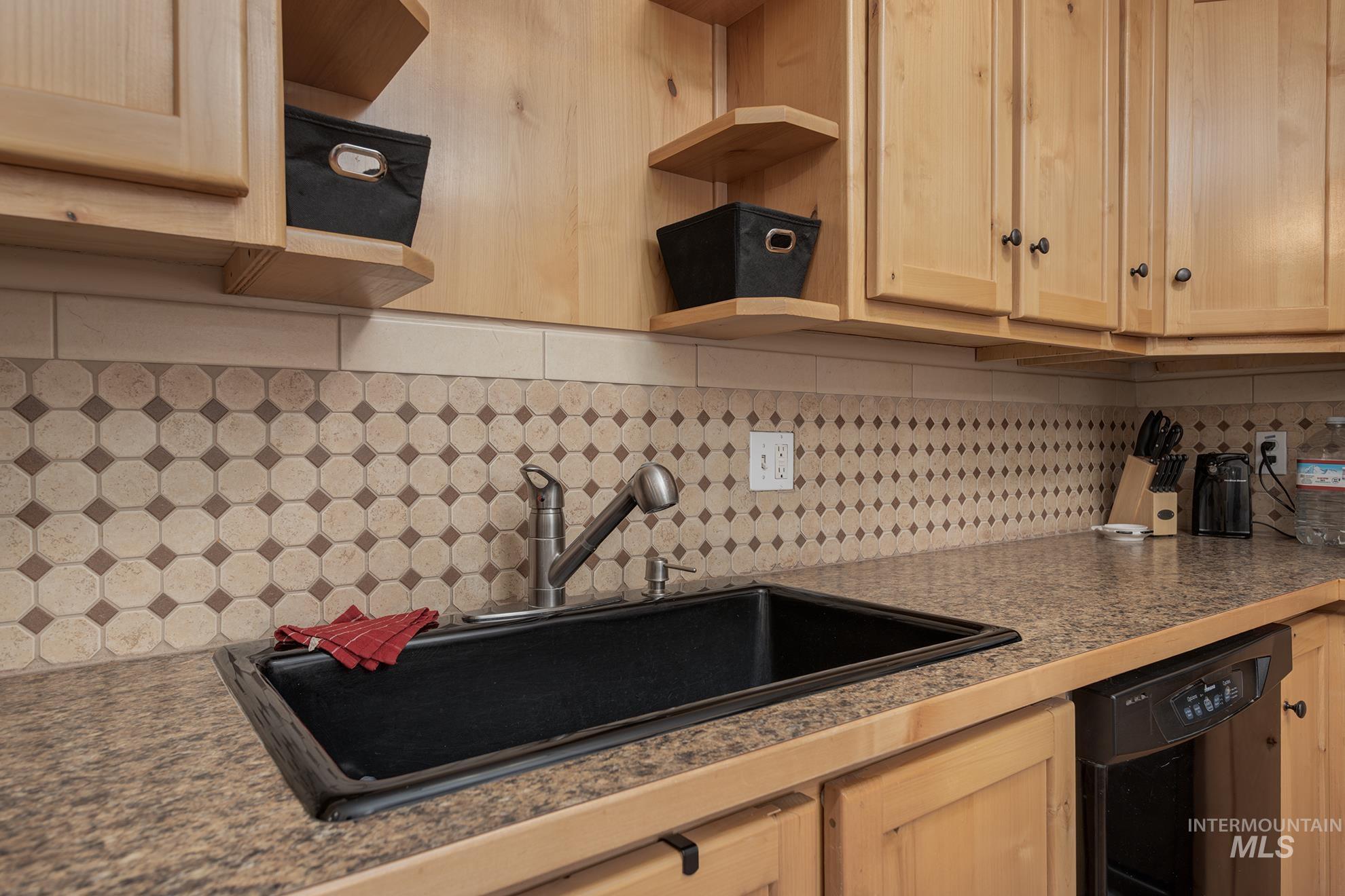 Kitchen featuring open shelves, dishwasher, light wood finish cabinetry, and tasteful backsplash
