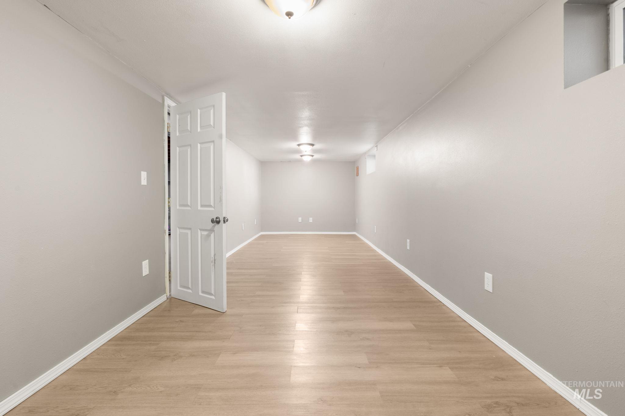 Finished basement with light wood-type flooring and baseboards