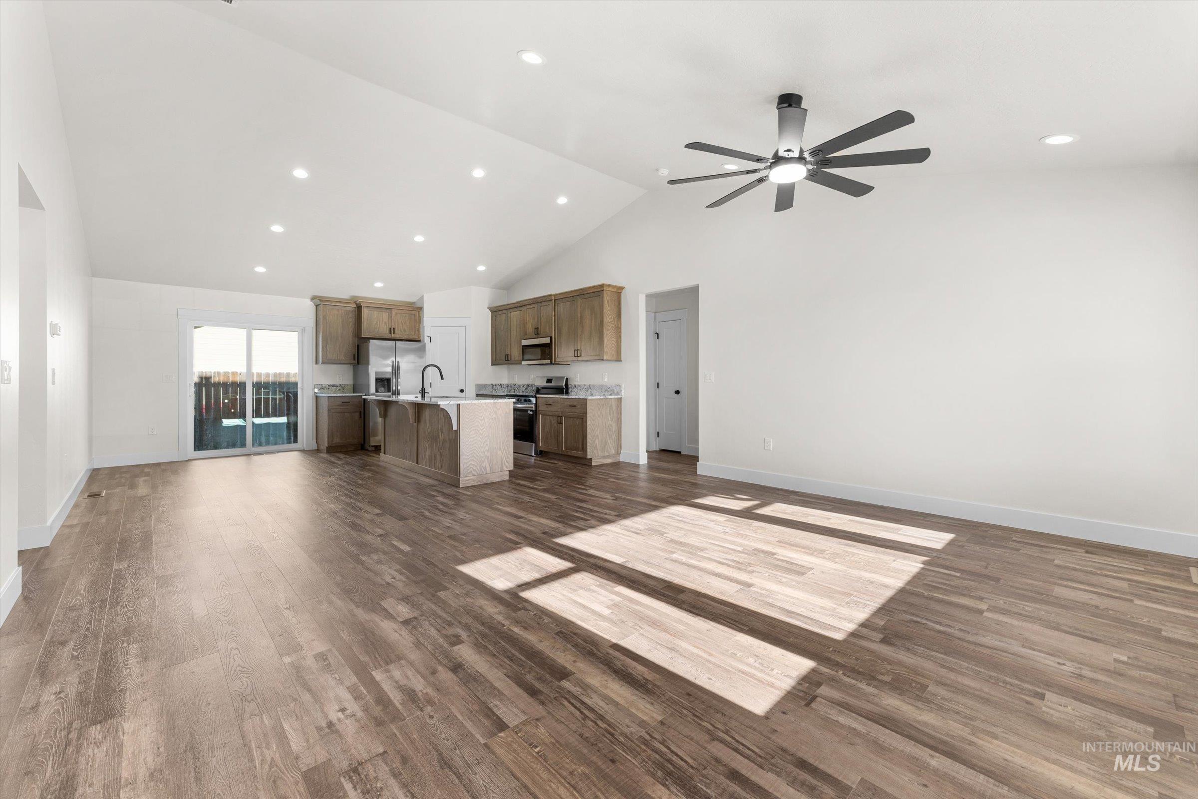 Unfurnished living room featuring recessed lighting, dark wood-type flooring, high vaulted ceiling, and ceiling fan