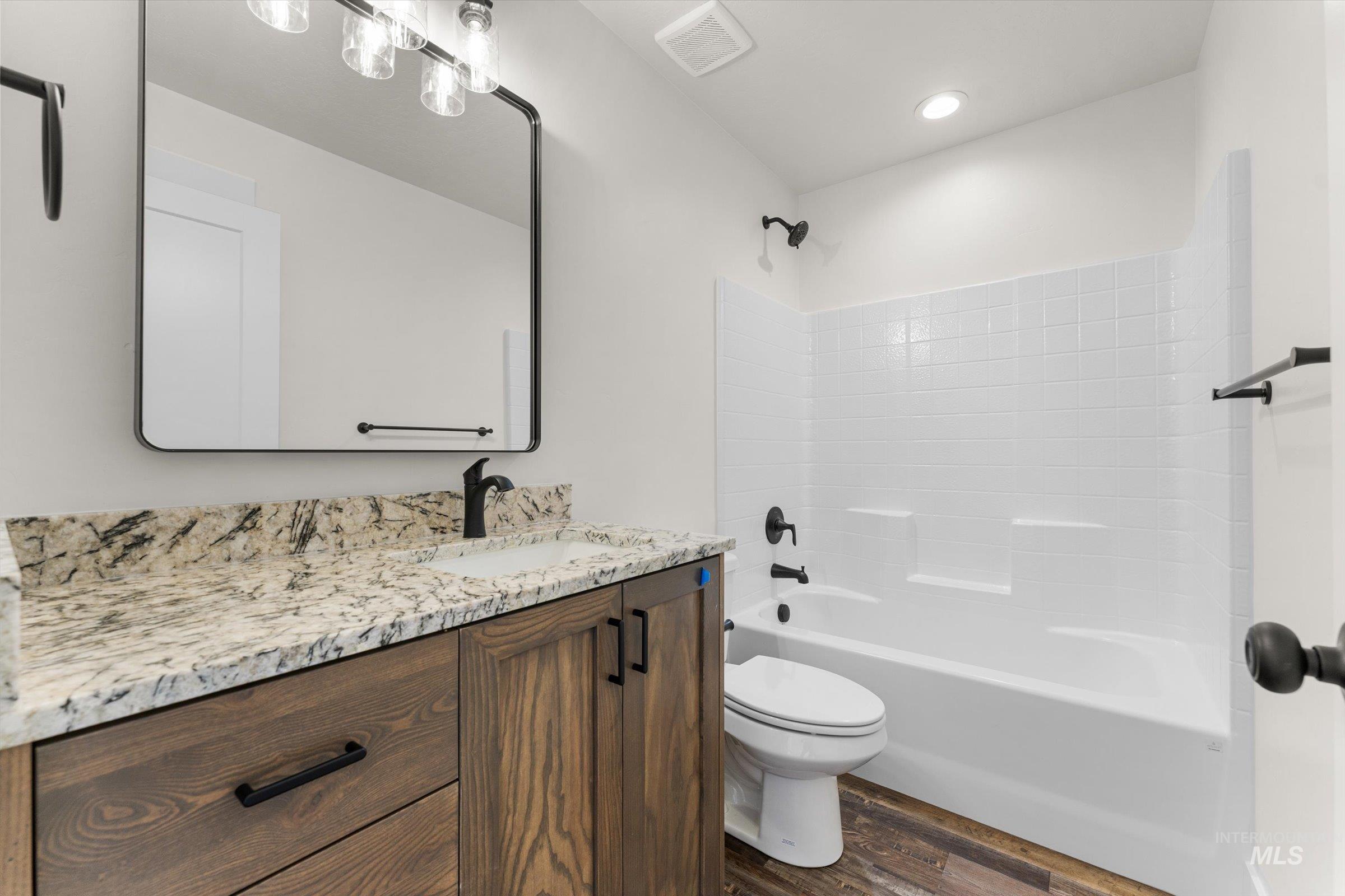 Bathroom featuring vanity,  shower combination, and dark wood-type flooring