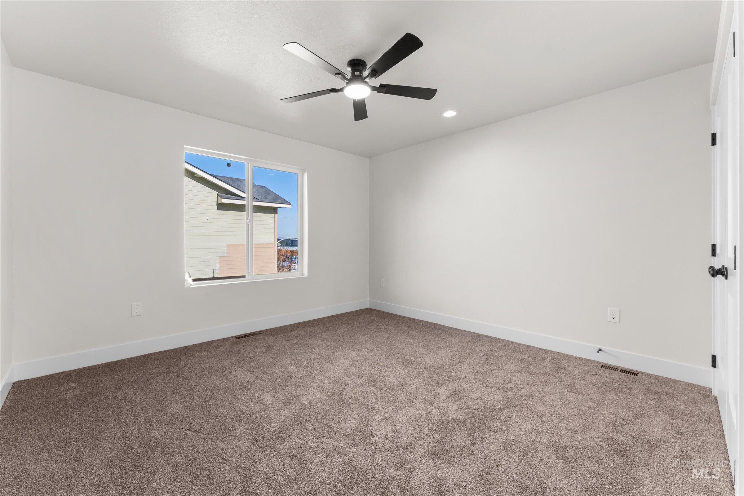 Spare room featuring light colored carpet, a ceiling fan, and recessed lighting
